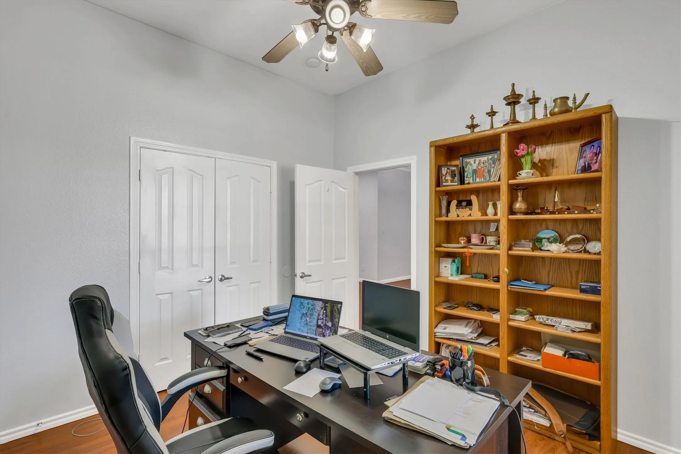Wood-finish flooring throughout, ceiling fan with light fixture, and white wall paint