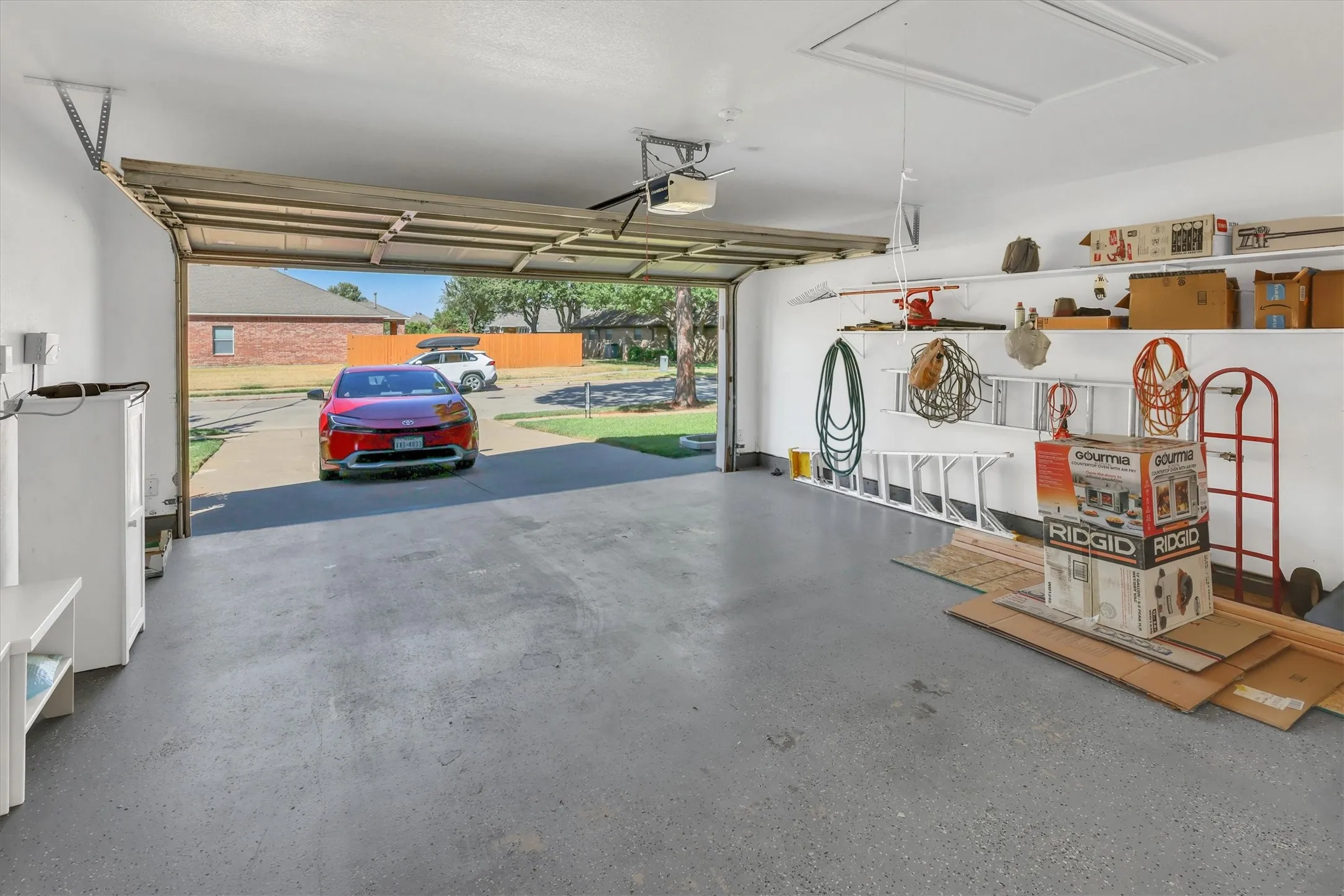 Attached garage with epoxy-coated flooring, built-in shelving, and an automatic garage door opener
