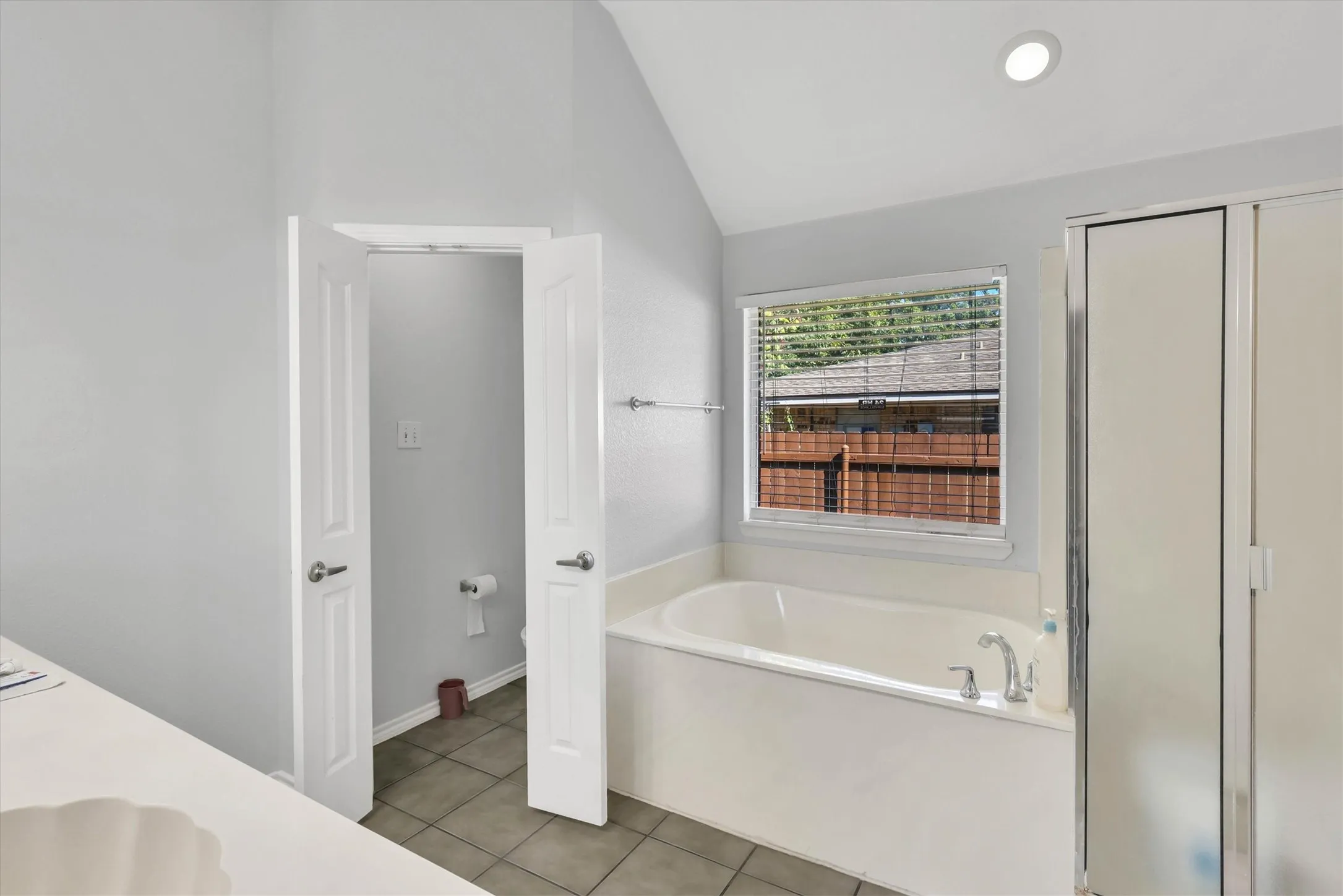 Soaking tub with a window, tile flooring, and a glass-enclosed shower