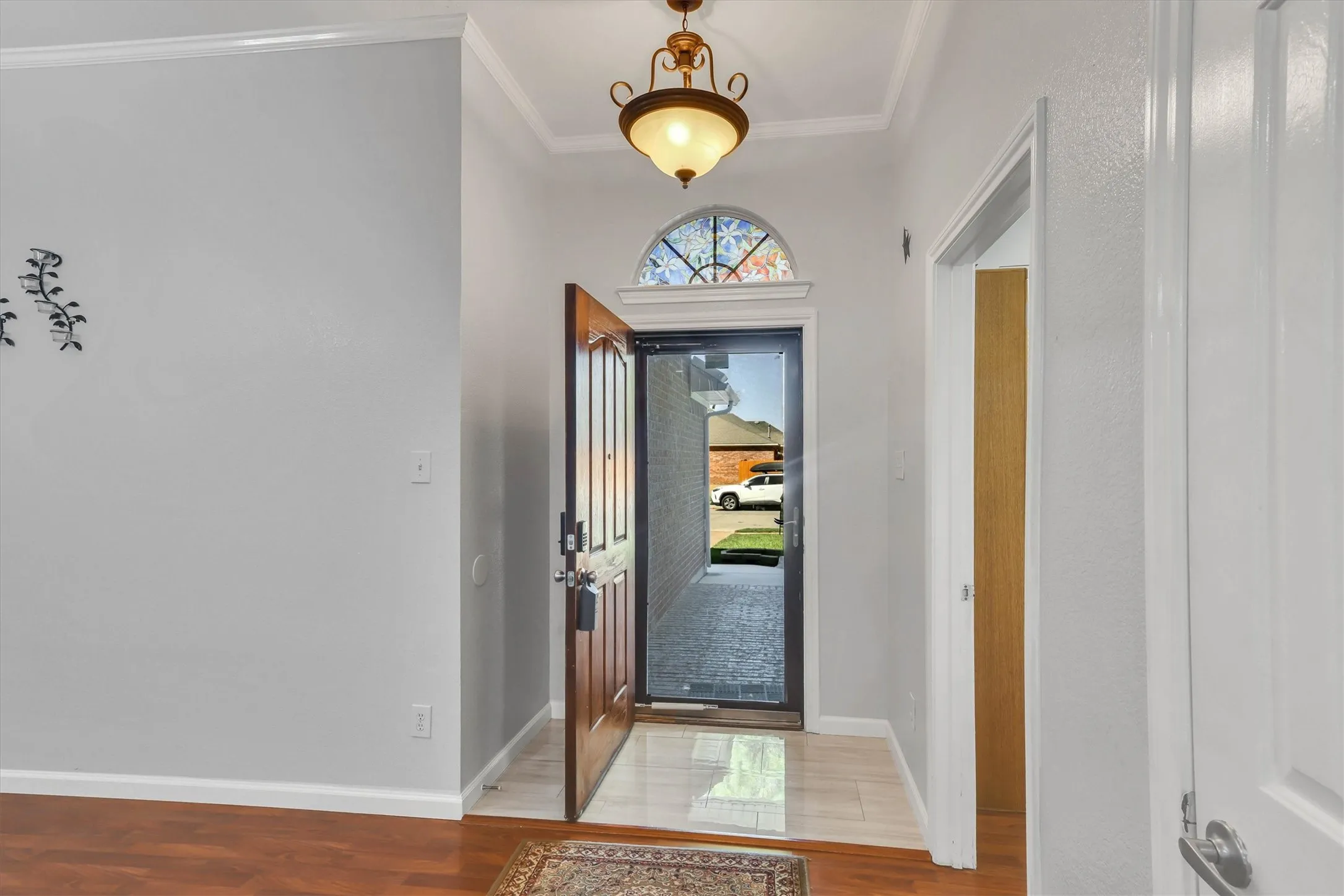 Entryway featuring wood-finish flooring and tile, a decorative transom window, and an ornate ceiling fixture