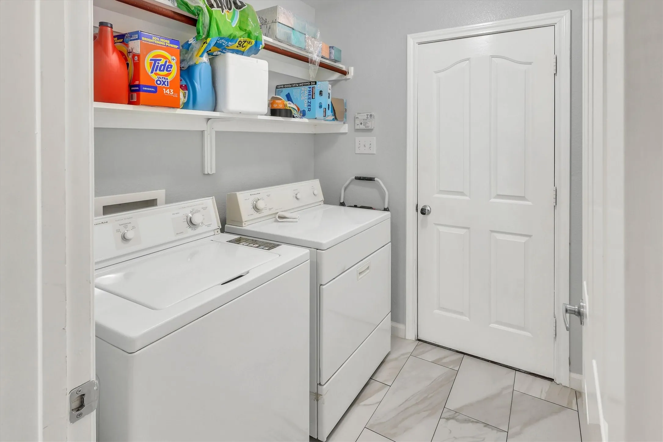 Utility area featuring white appliances, a paneled door, and two white floating shelves