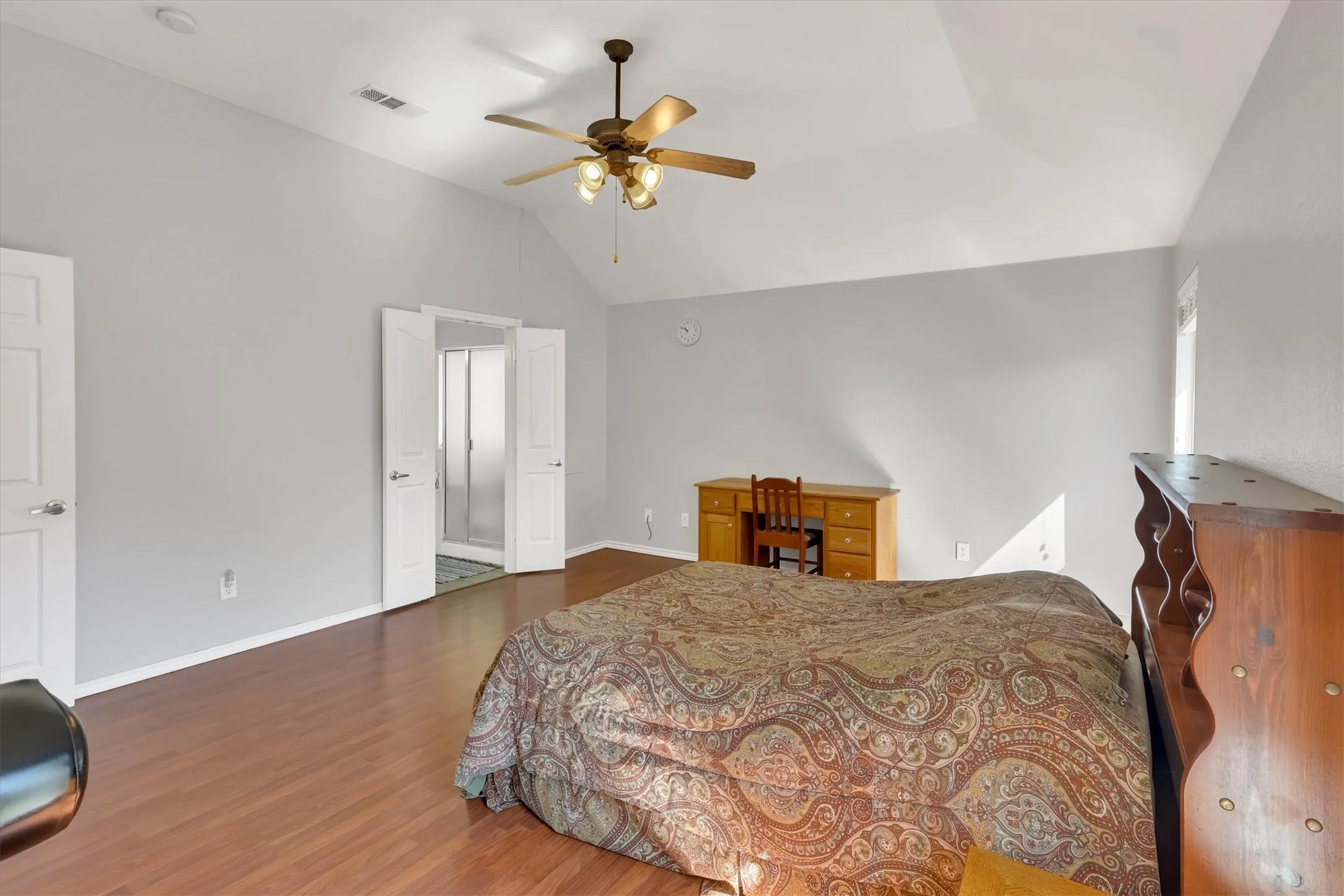 Vaulted ceiling with ceiling fan, wood-finish flooring, light-toned wall paint, and white paneled doors