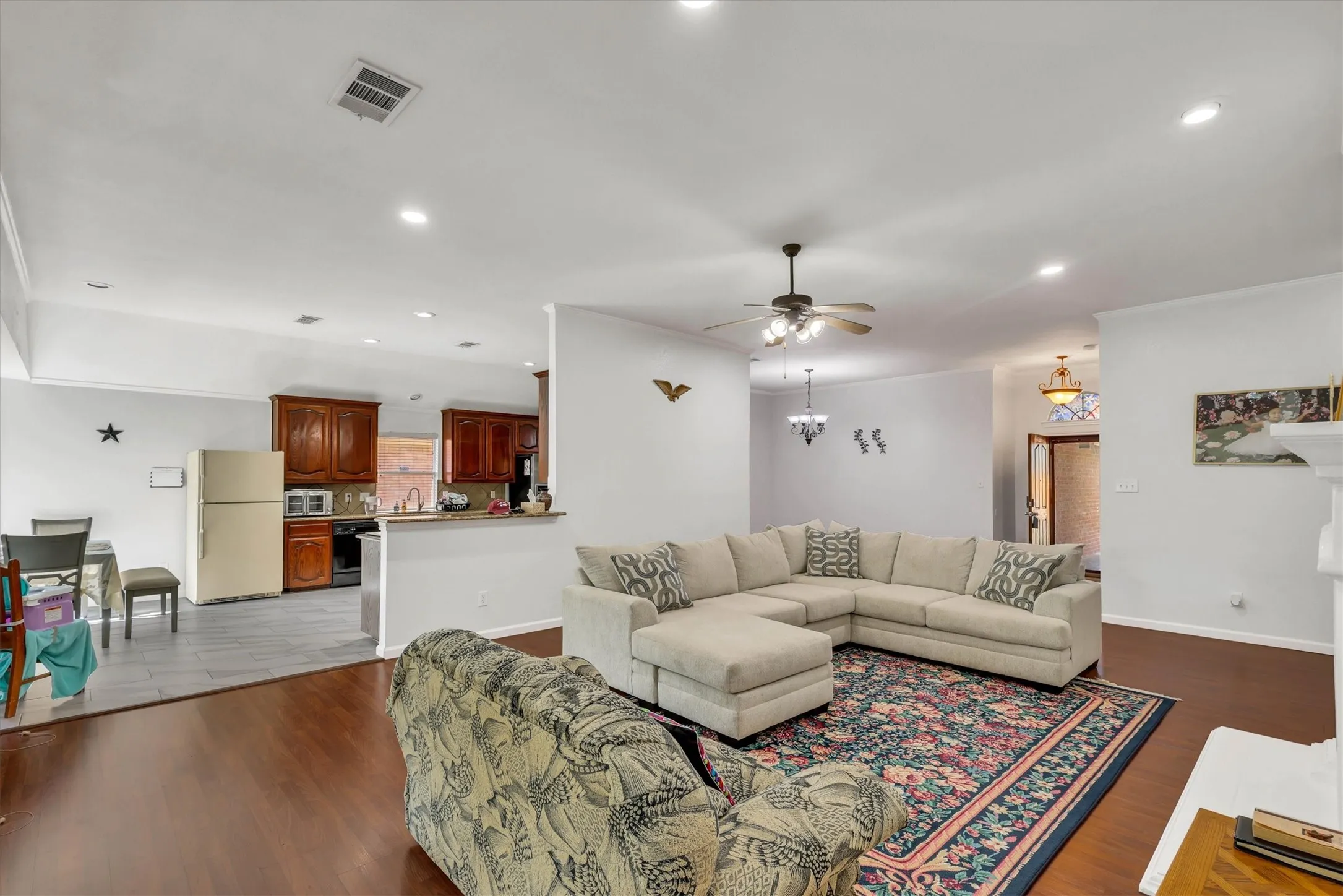 Hardwood flooring, recessed lighting, ceiling fan, crown molding, and a partial height wall opening to the kitchen