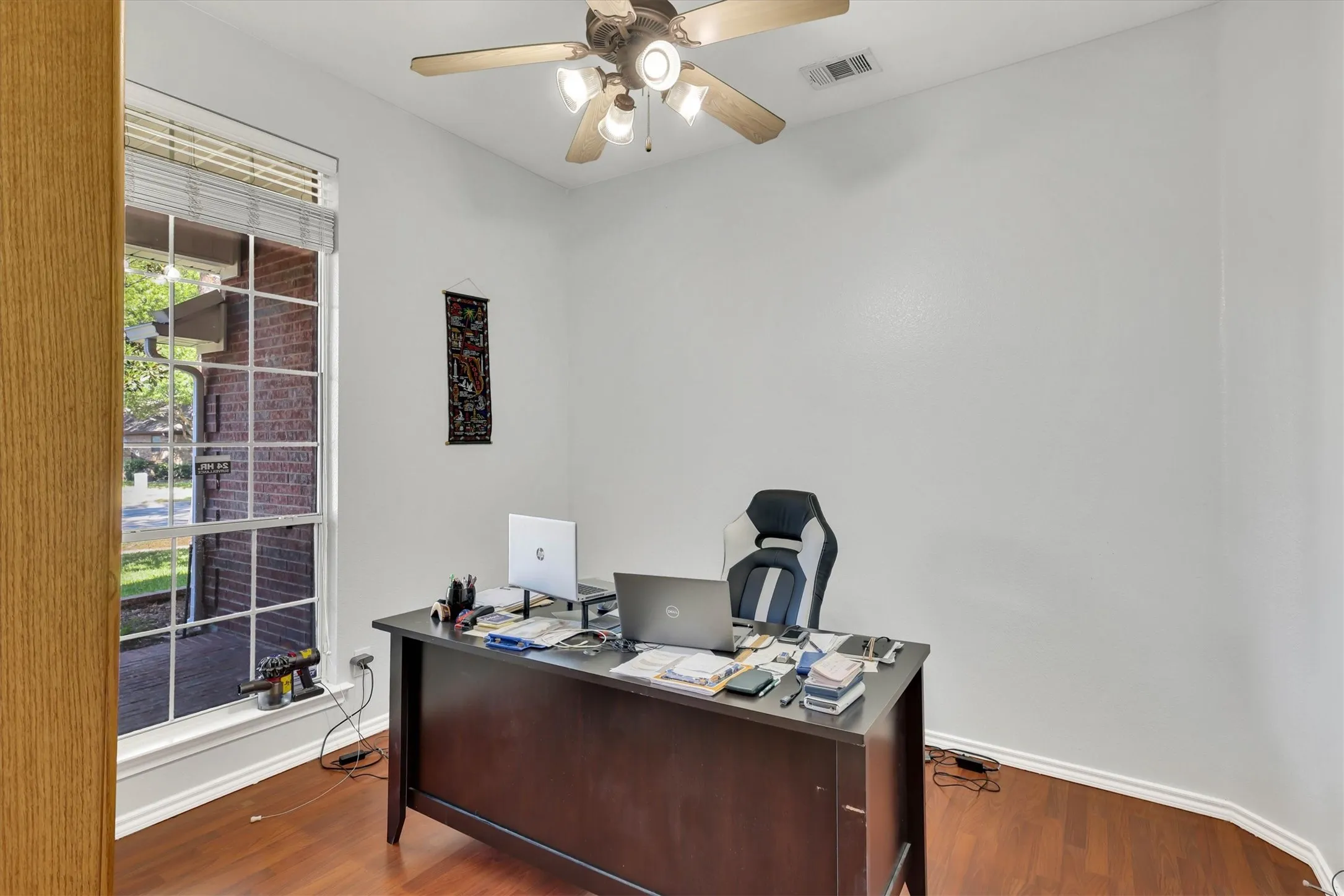 Wood-finish flooring, ceiling fan with integrated lighting, and a large window with blinds
