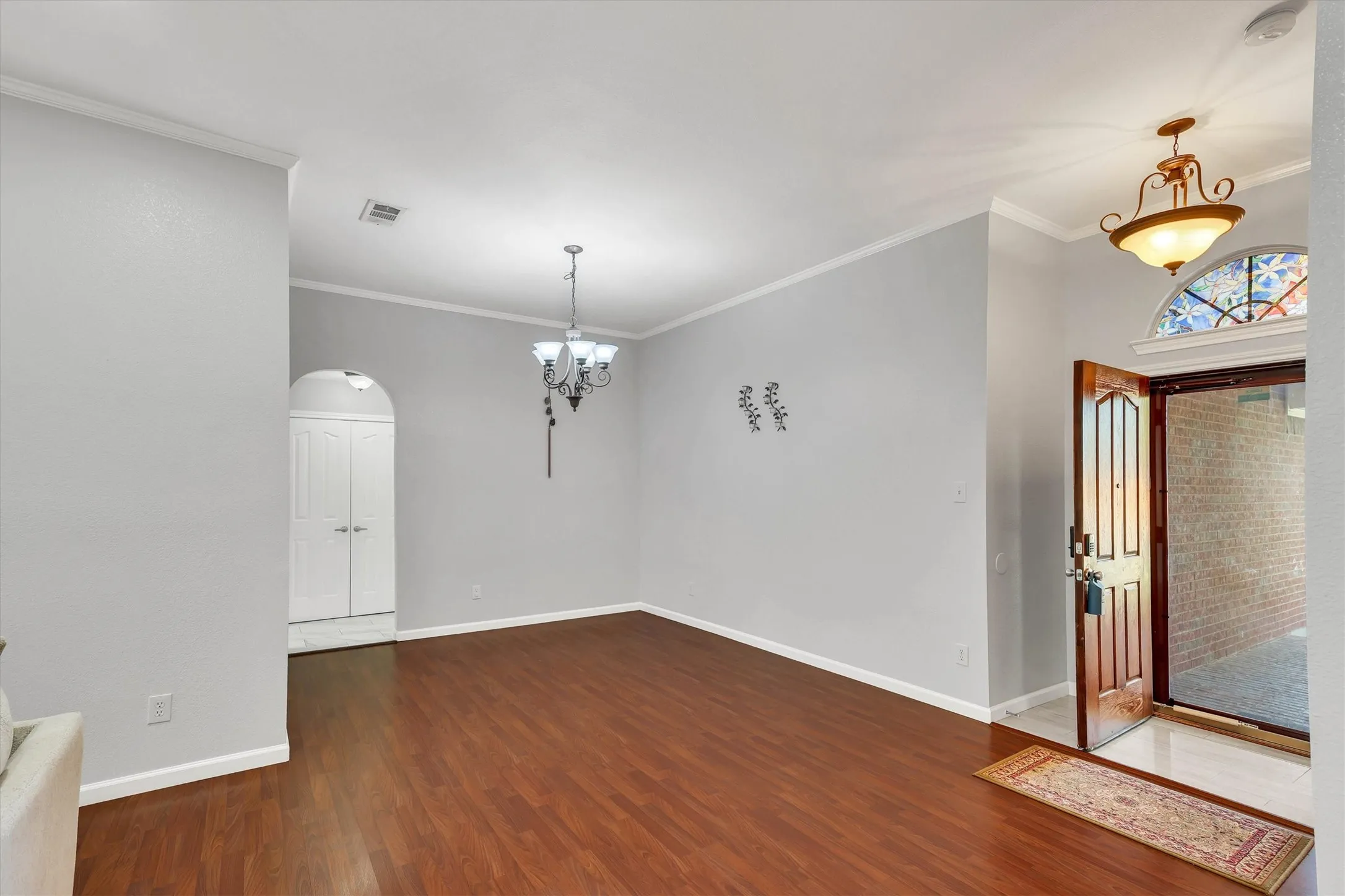 Wood-finish flooring, crown molding, and a chandelier illuminate the interior
