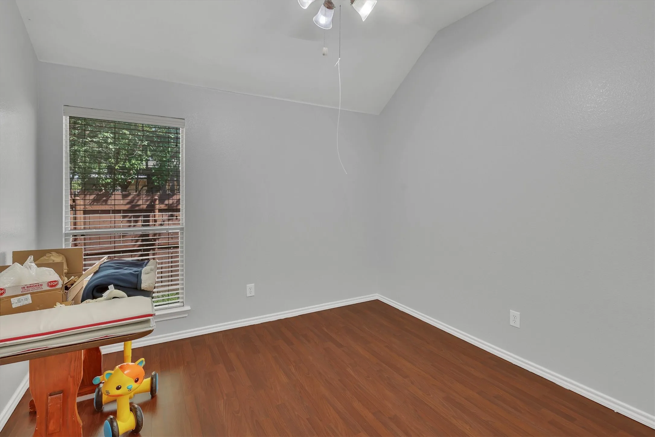 Vaulted ceiling with a ceiling fan, wood-finish flooring, and window with blinds