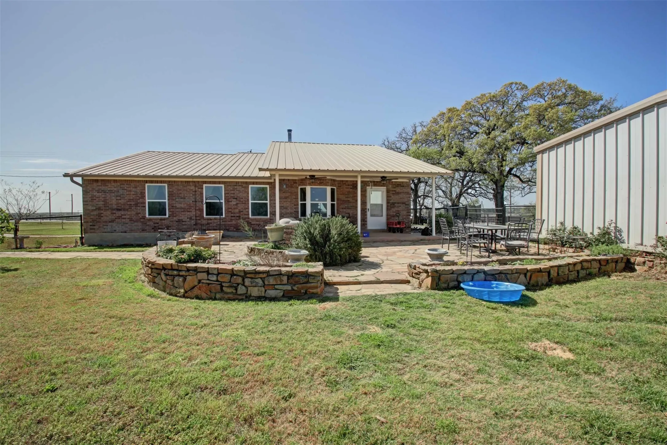 View of the house from the hay field. You can see the beautiful stonework surrounding the patio area.