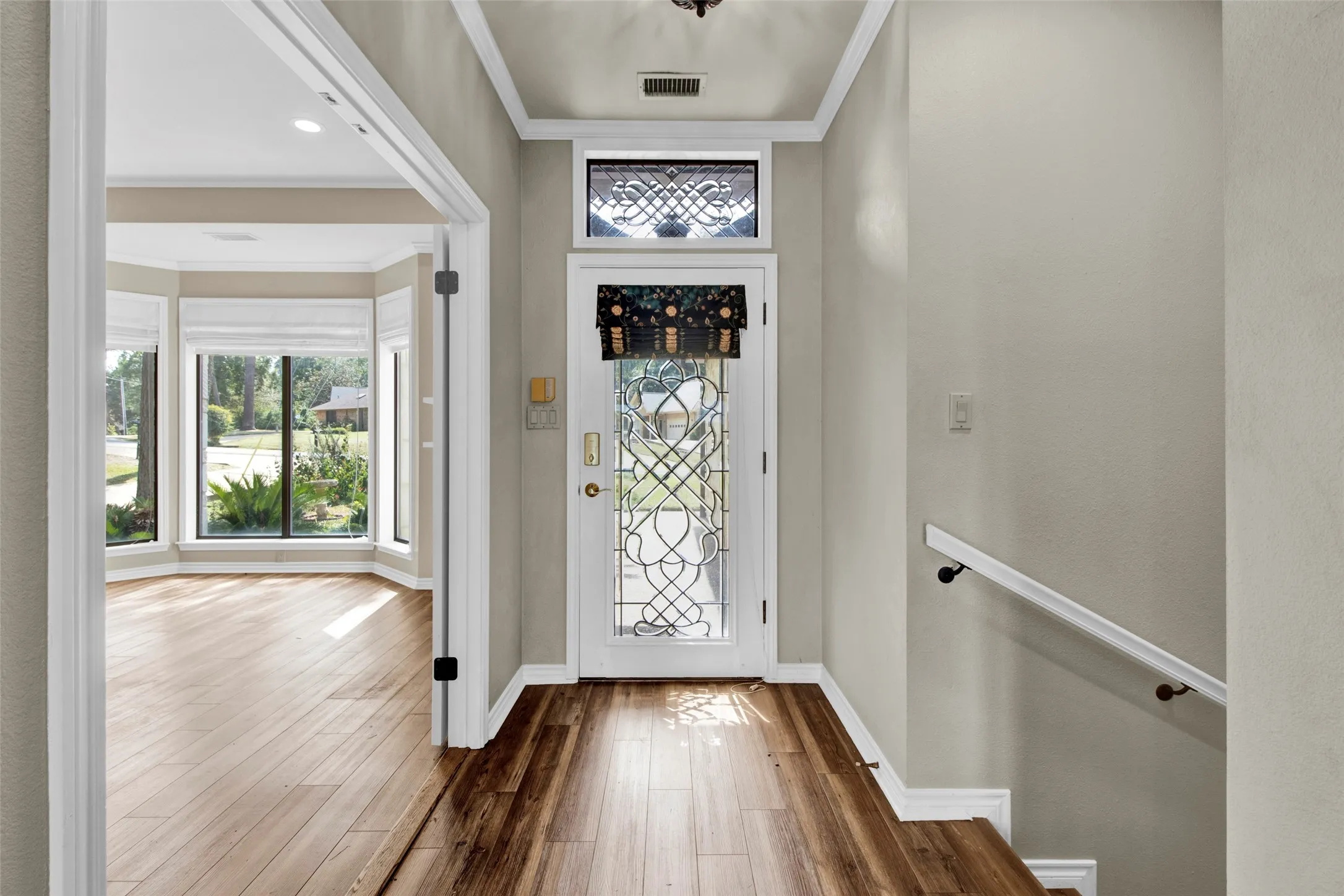 Entryway featuring a decorative glass front door, transom window, and wood-finish flooring