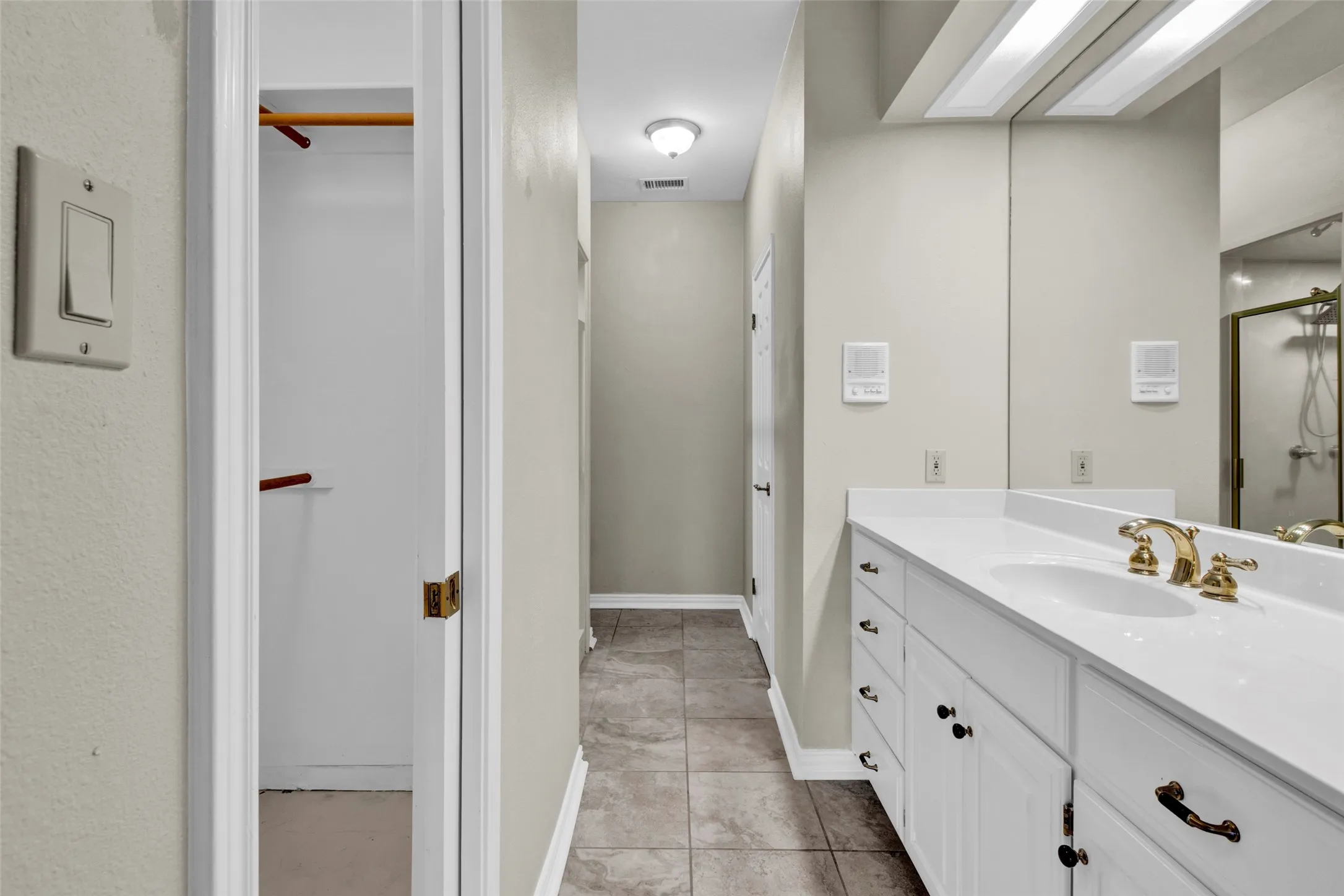 Bathroom featuring a single vanity with a white countertop, gold-toned faucet, and a large wall-mounted mirror