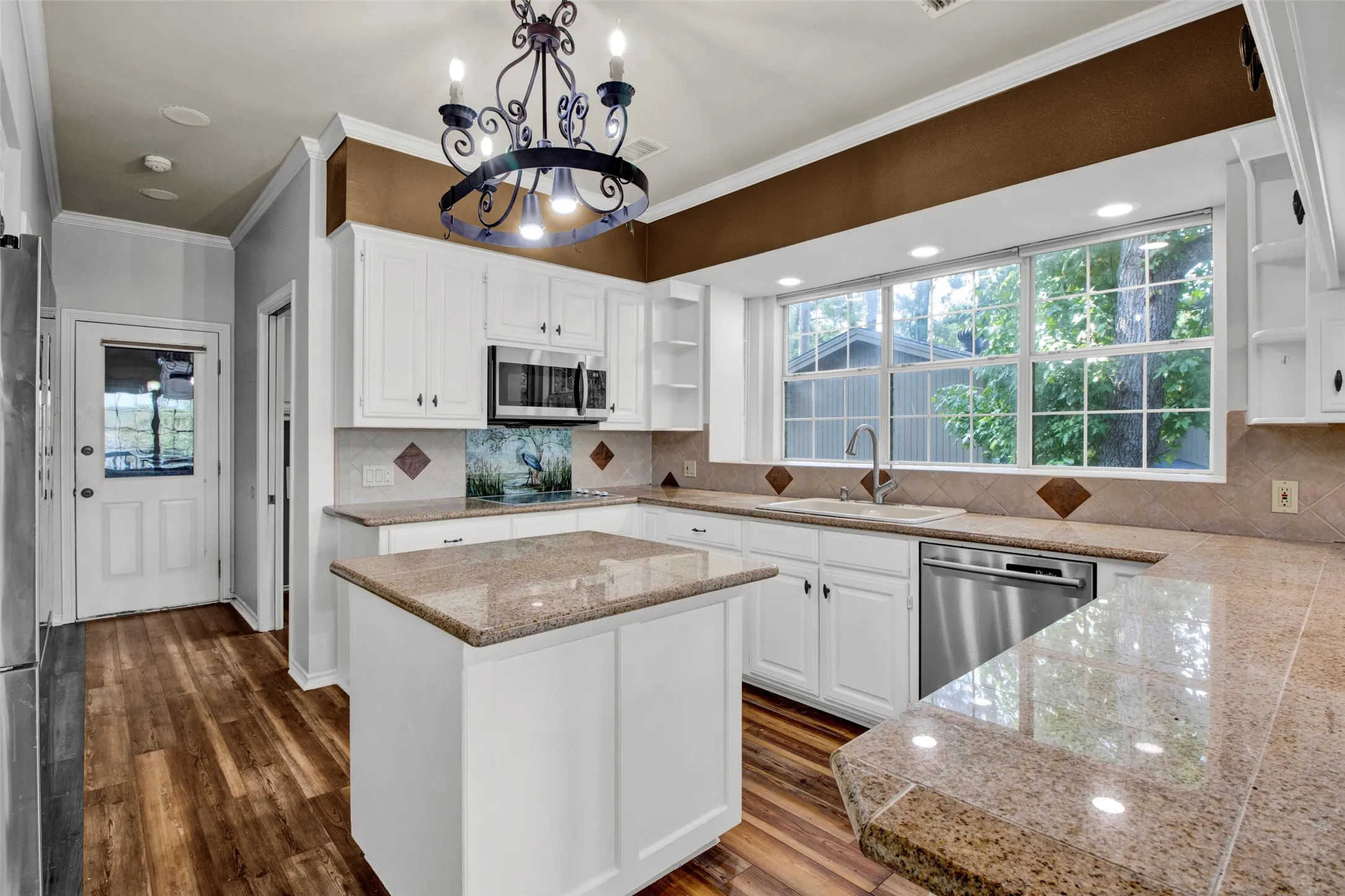 Kitchen featuring white cabinetry, granite-finish countertops, stainless steel appliances, a center island, and wood-finish flooring