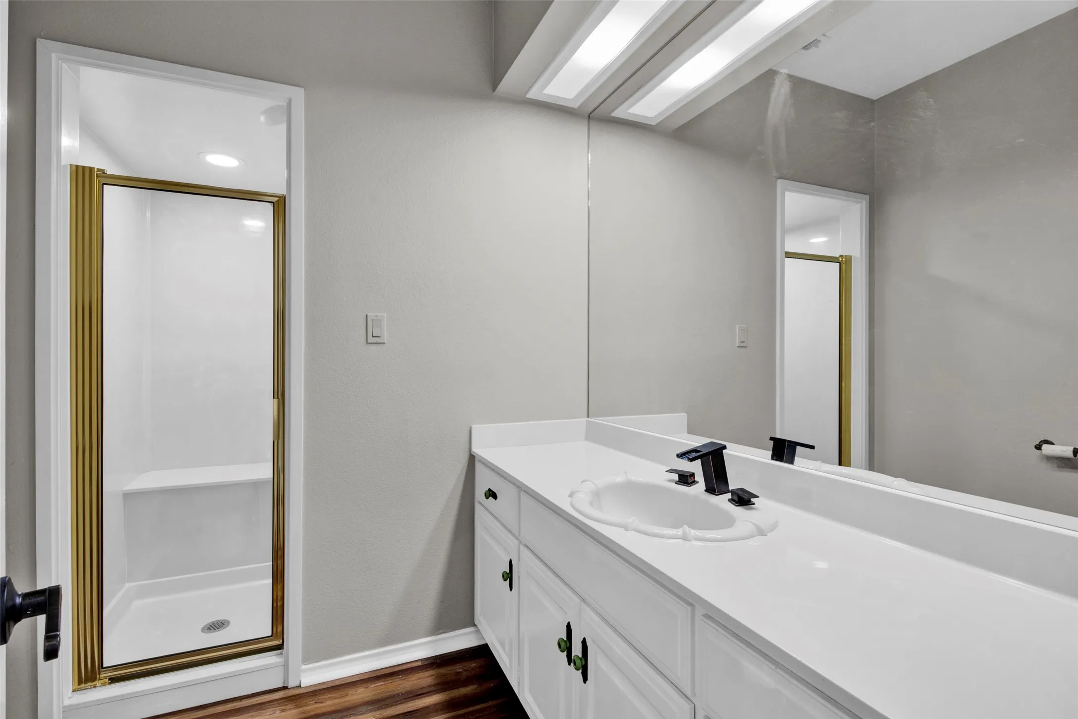 Vanity with an integrated sink, black hardware, and a framed mirror