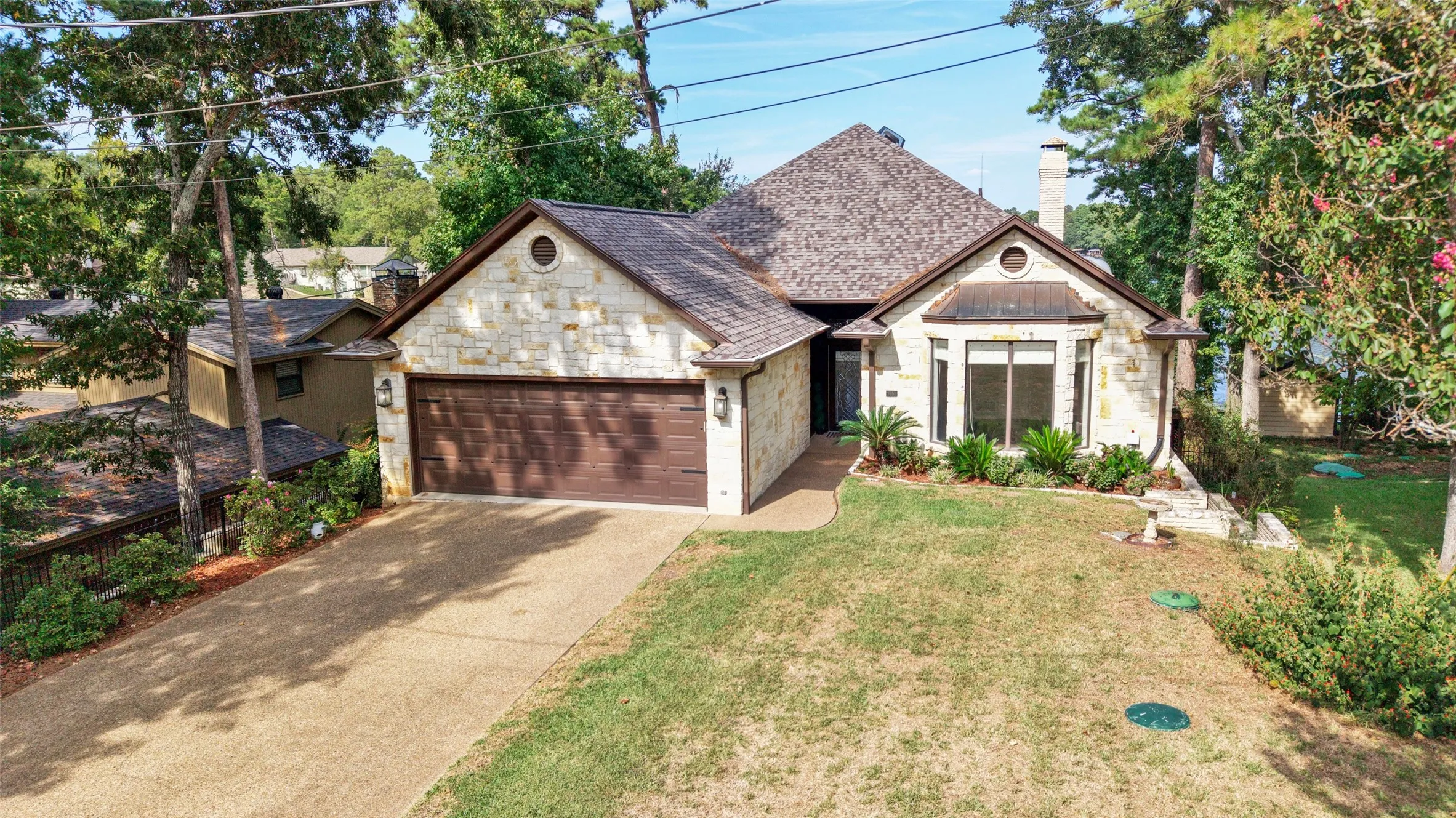 Stone exterior with a shingle roof and an attached two-car garage