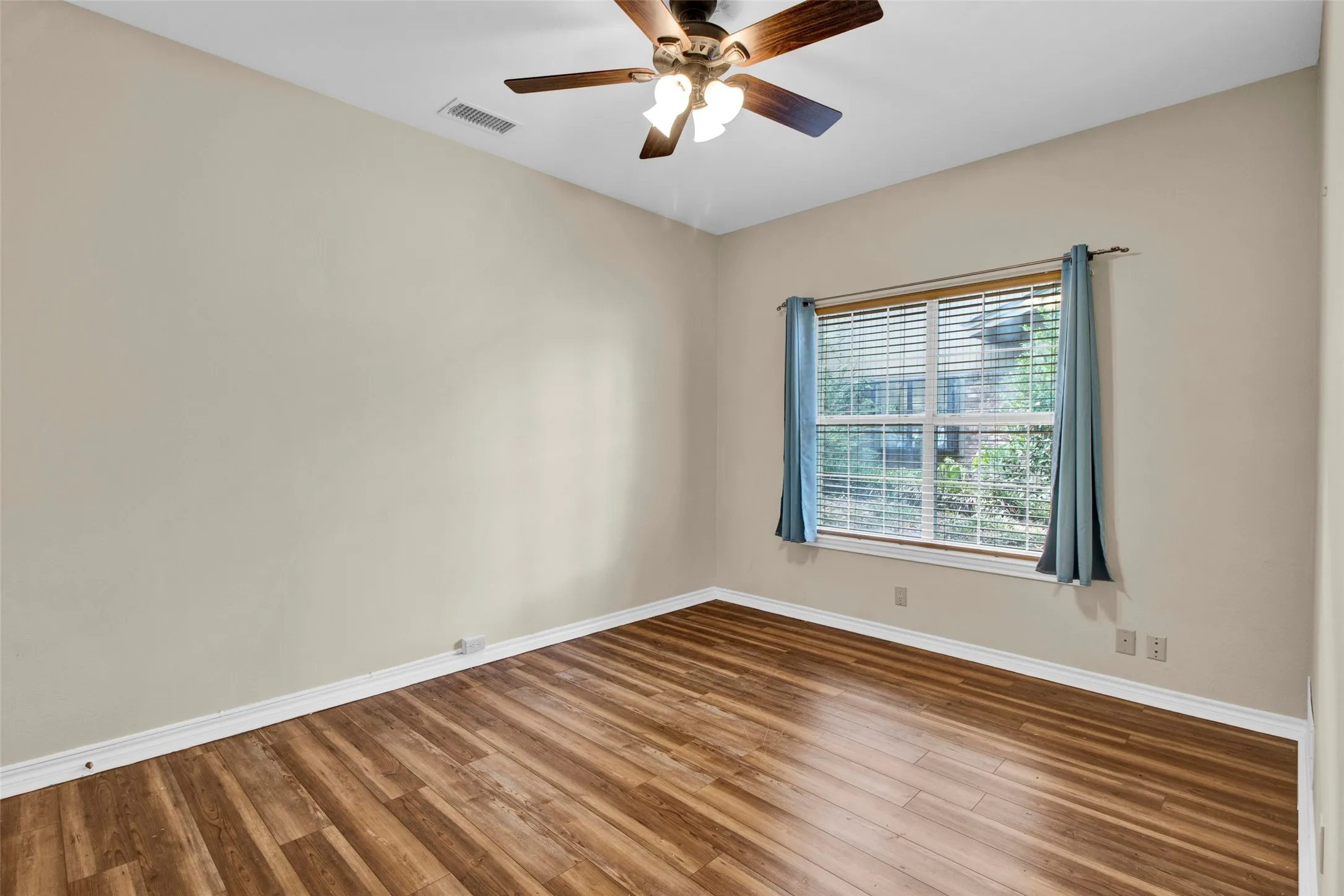 Wood-finish flooring, neutral wall tones, and a window with horizontal blinds