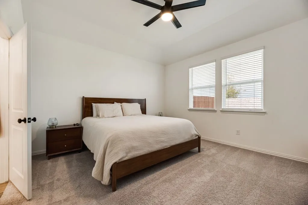 Vaulted ceiling with a ceiling fan, two windows, wall-to-wall carpeting, and a white paneled door