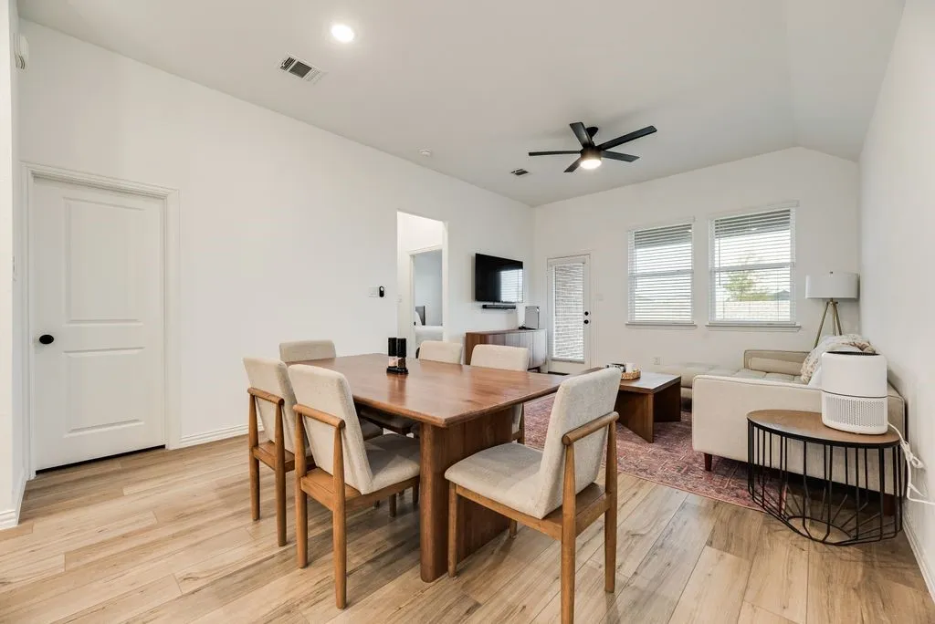 Vaulted ceiling with a ceiling fan, recessed lighting, wood-finish flooring, white paneled doors, and multiple windows with blinds