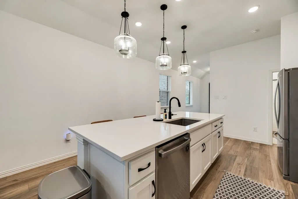 Kitchen island with white cabinetry, a solid surface countertop, an undermount sink, and a matte black faucet