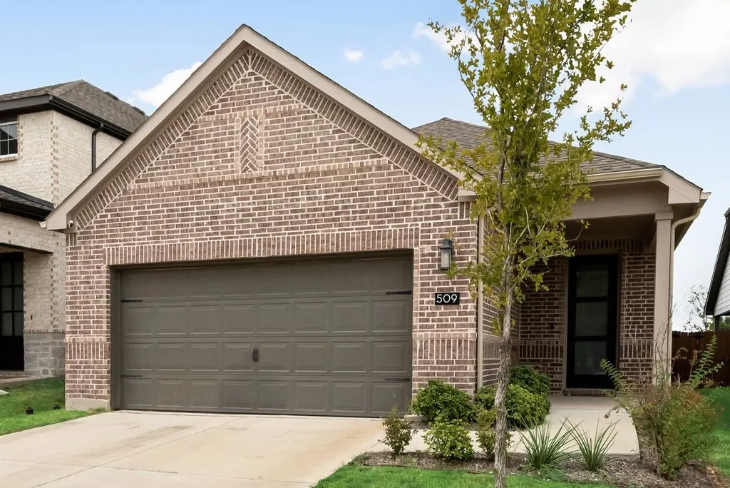 Brick facade with a covered entry, attached garage, and concrete driveway