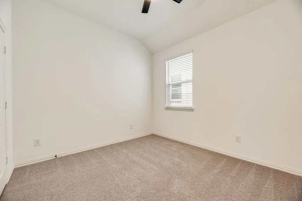 Vaulted ceiling featuring a ceiling fan, neutral wall paint, window with blinds, and carpet flooring