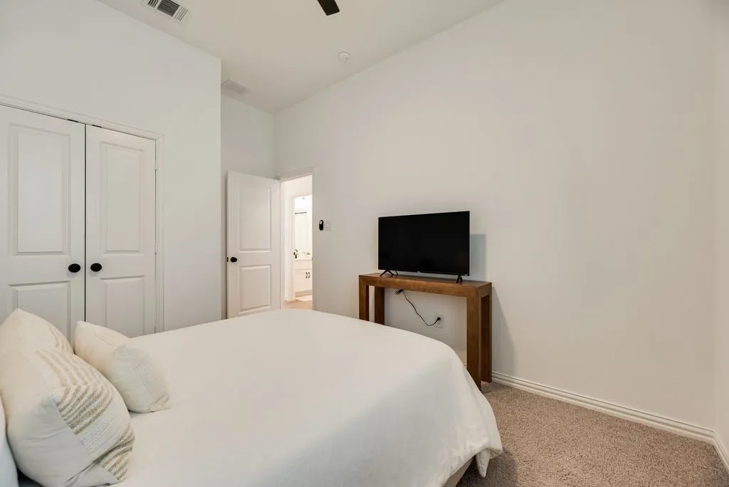 Carpeted flooring, two paneled doors with black hardware, and a ceiling fan