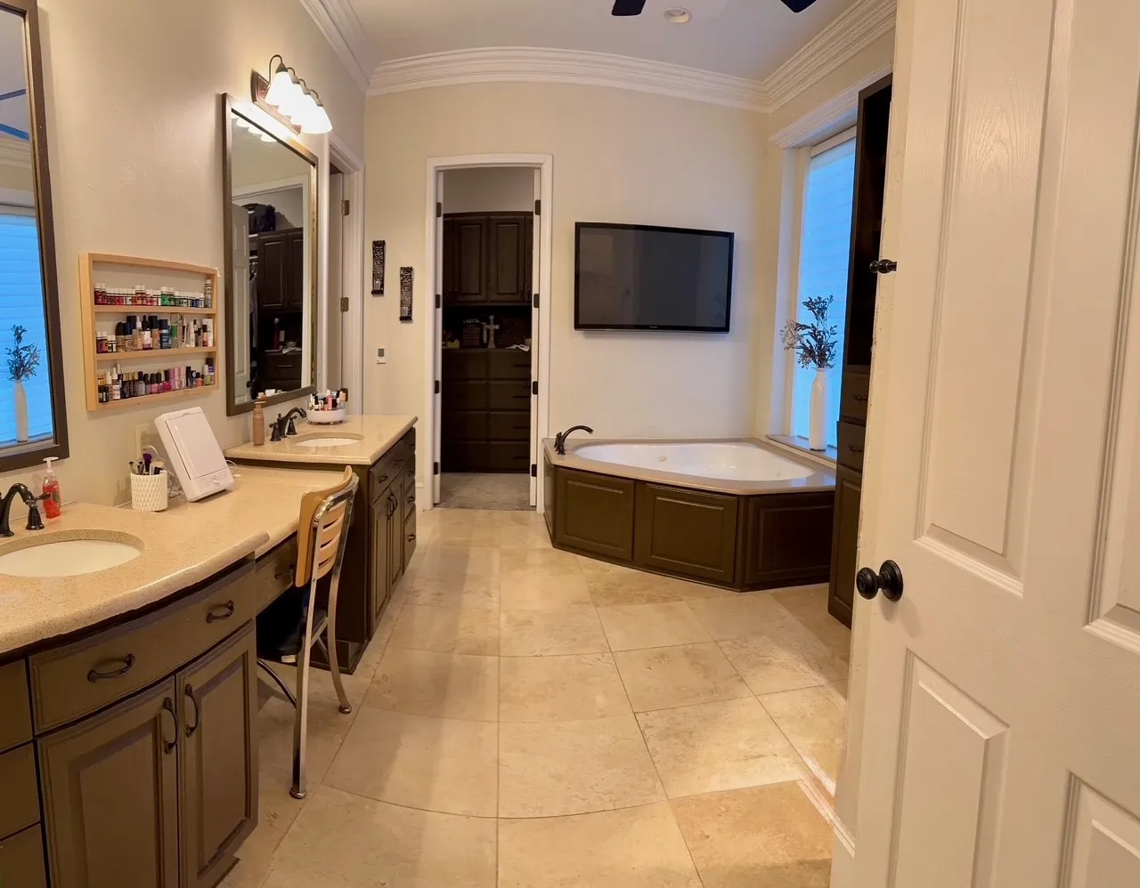 Dual vanities with undermount sinks, corner jetted tub, tile flooring, and crown molding