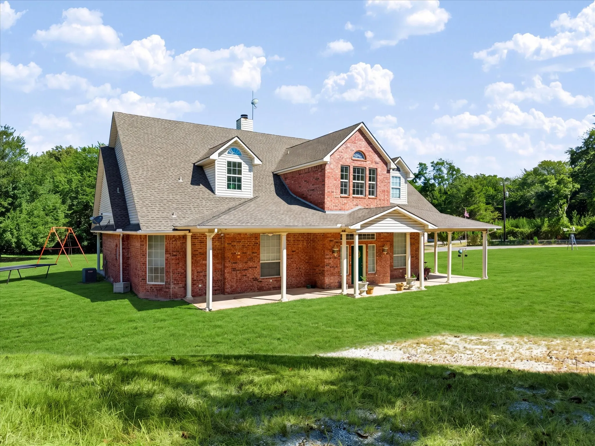 Brick exterior with white trim, covered front porch, dormer windows, and a shingle roof