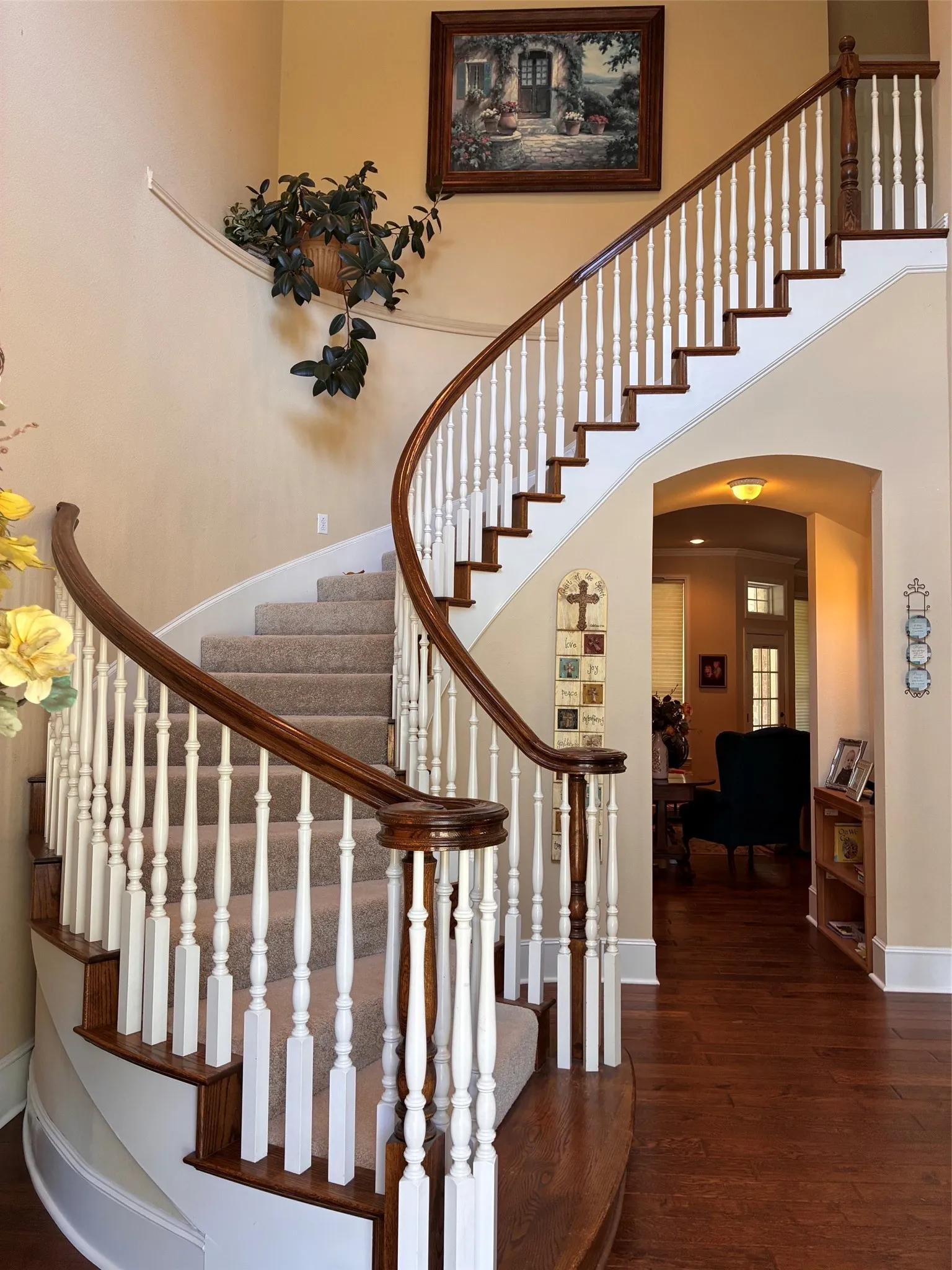 Curved staircase featuring wood-finish handrails, white balusters, and carpeted treads