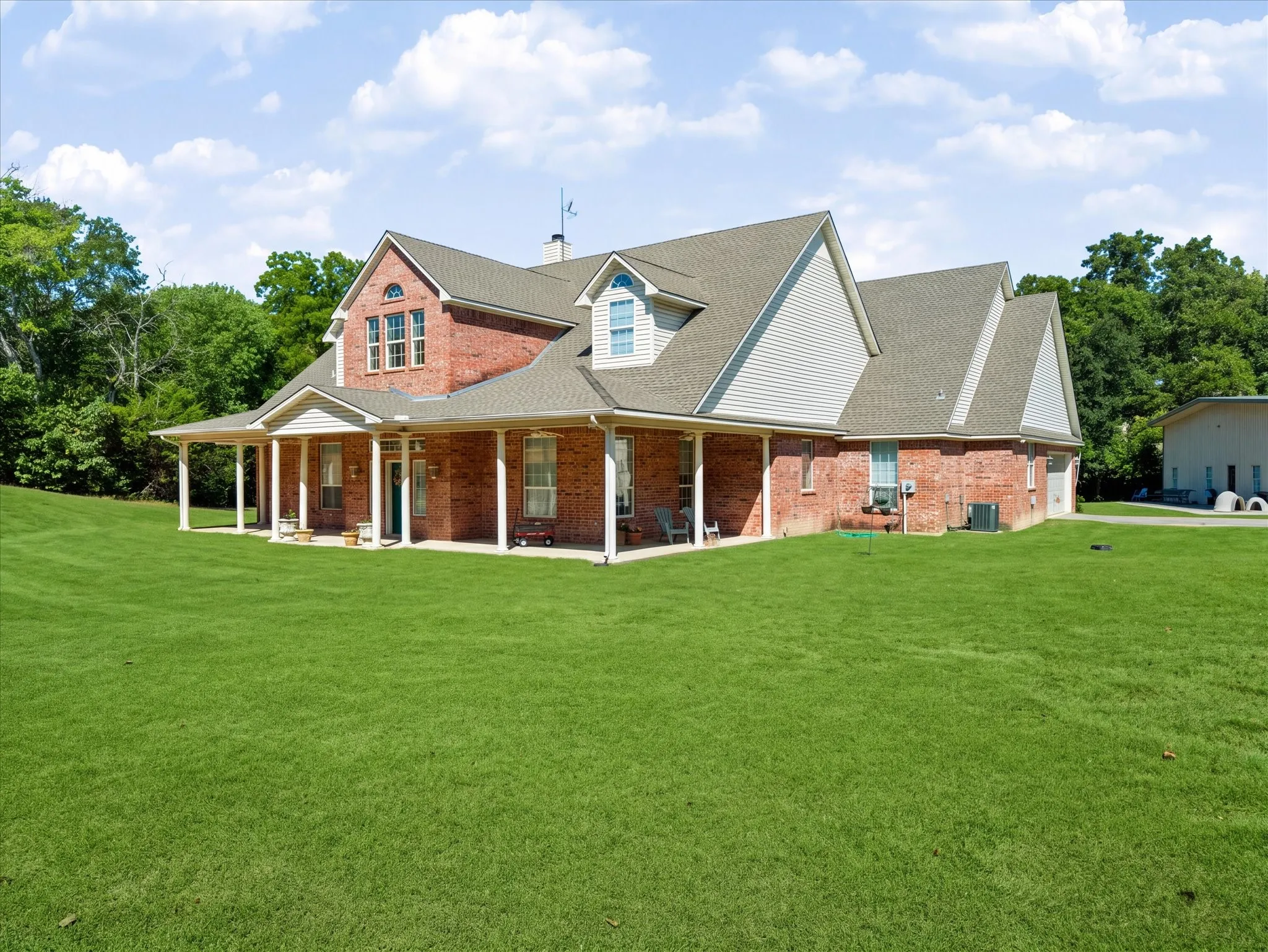 Brick and siding exterior with a covered wrap-around porch featuring white columns
