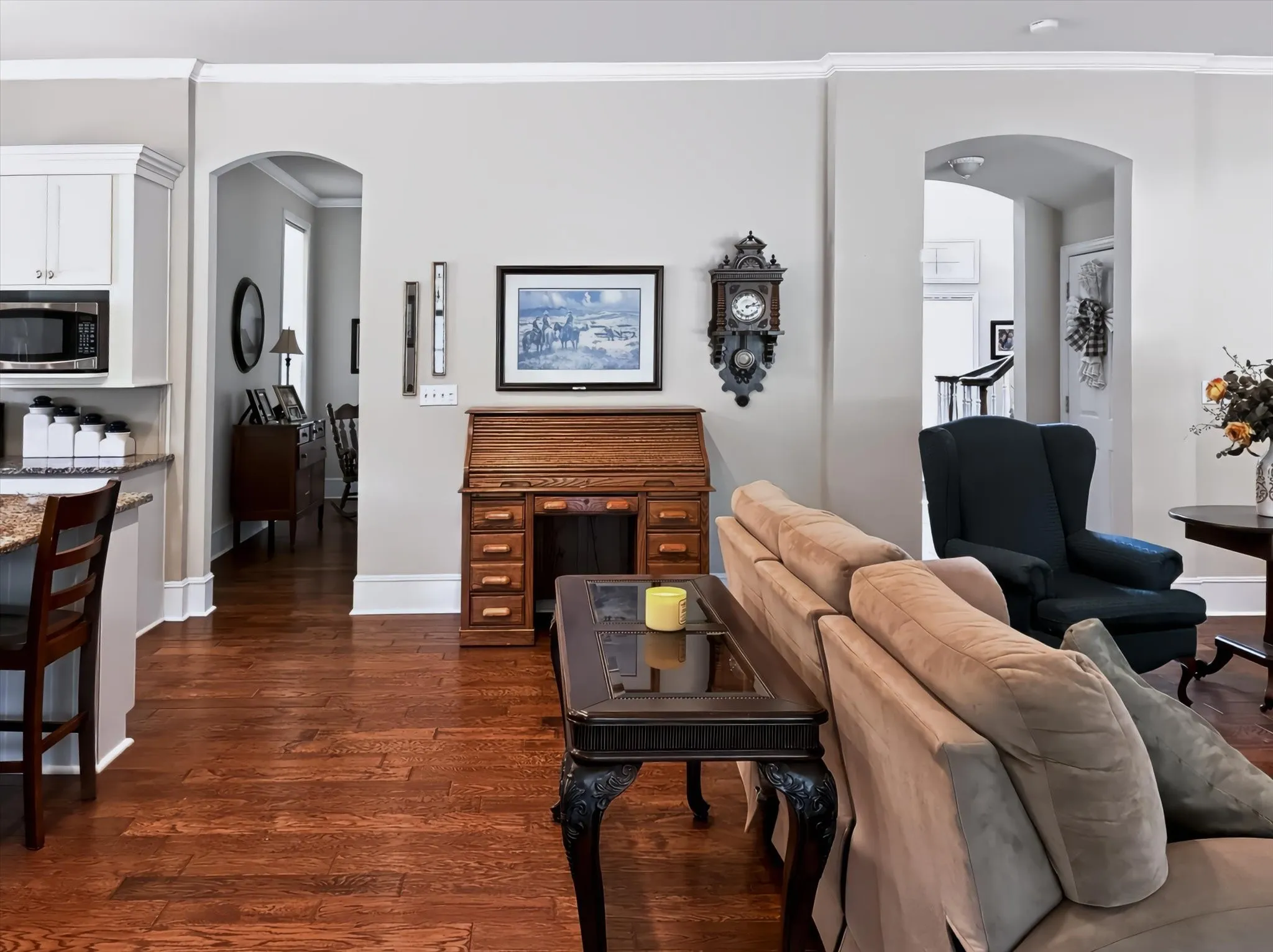 Wood-finish flooring throughout, arched doorways, white crown molding, built-in microwave, and granite countertops