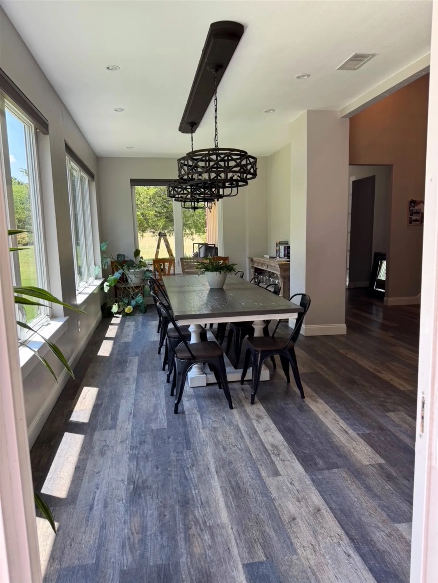 Wood-finish flooring throughout, multiple large windows, recessed ceiling lighting, and two decorative ceiling light fixtures