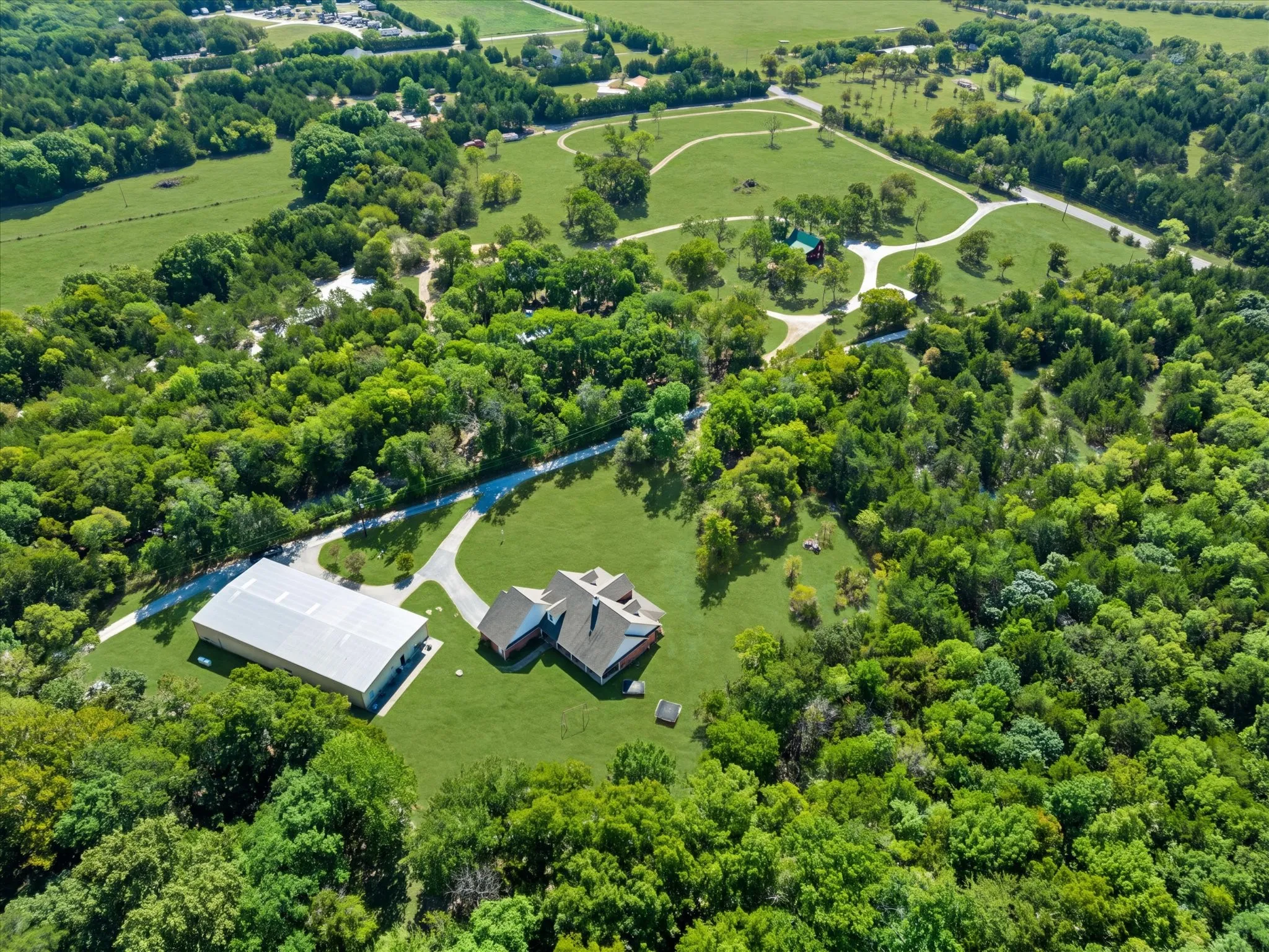 Expansive property featuring a main residence, large outbuilding, and extensive tree coverage