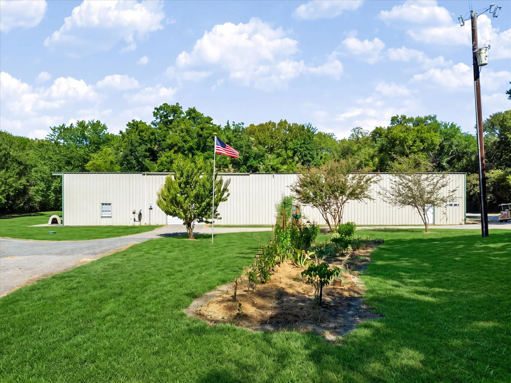 Expansive grounds featuring a gravel drive, manicured lawn, and mature trees
