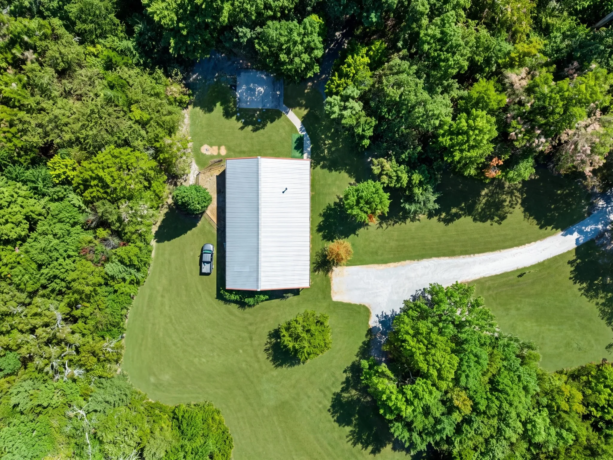Expansive grounds with a gravel driveway, lush green lawn, and mature trees
