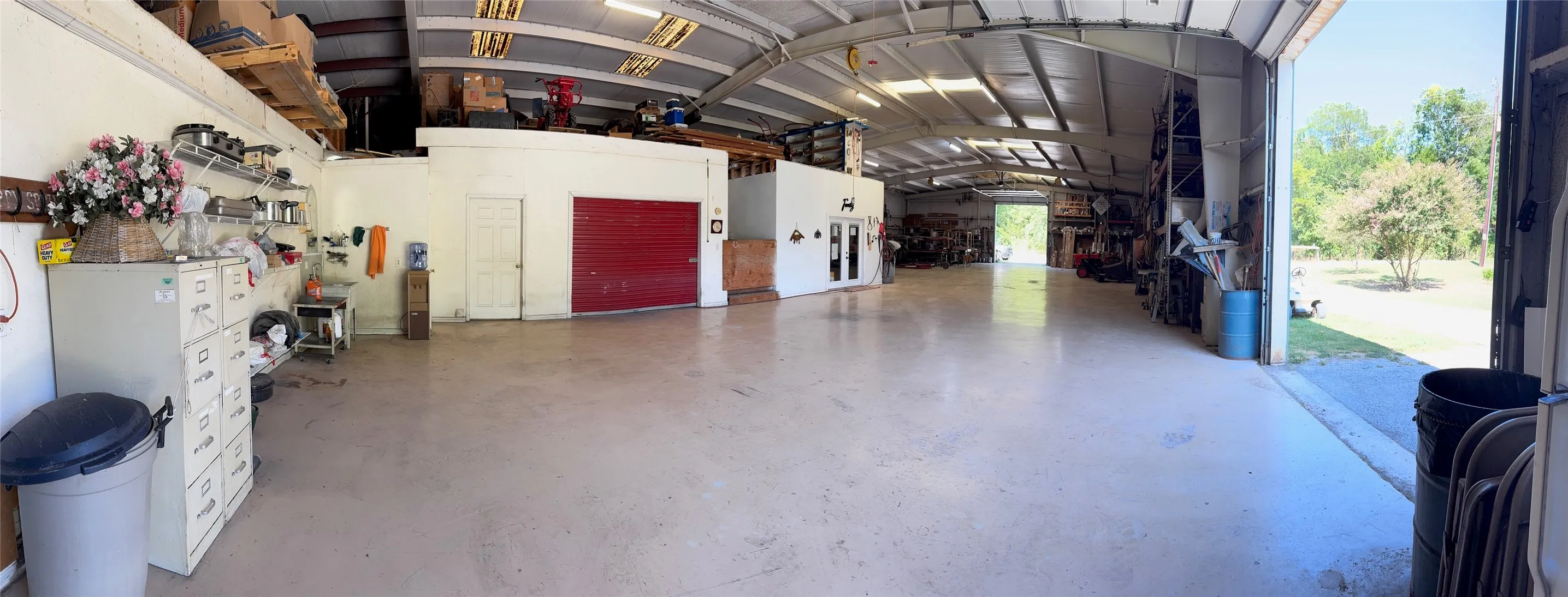 Expansive warehouse space featuring a concrete floor, high ceilings, multiple roll-up doors, and an integrated office area
