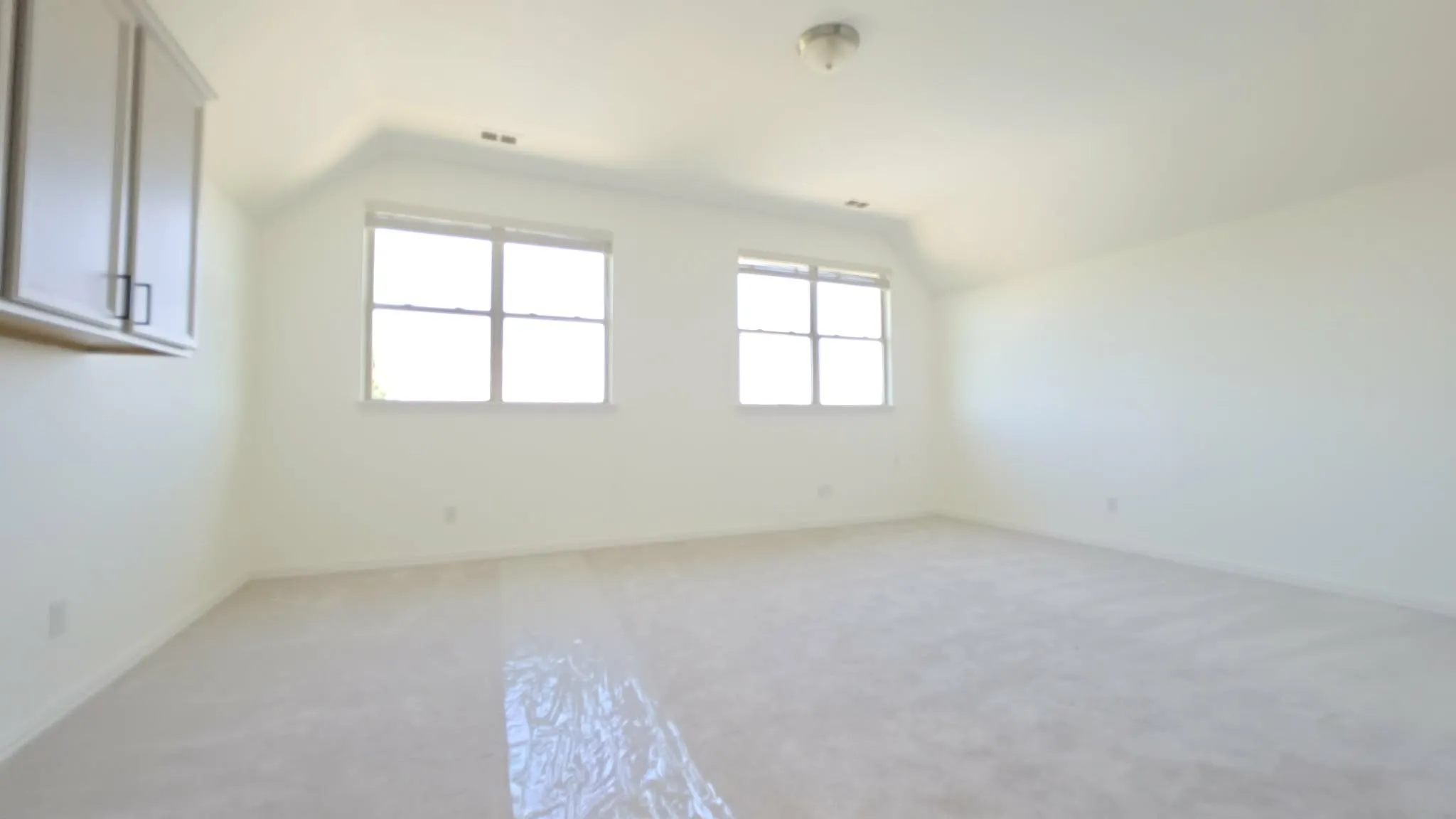Spacious room with light-colored carpeting and white walls