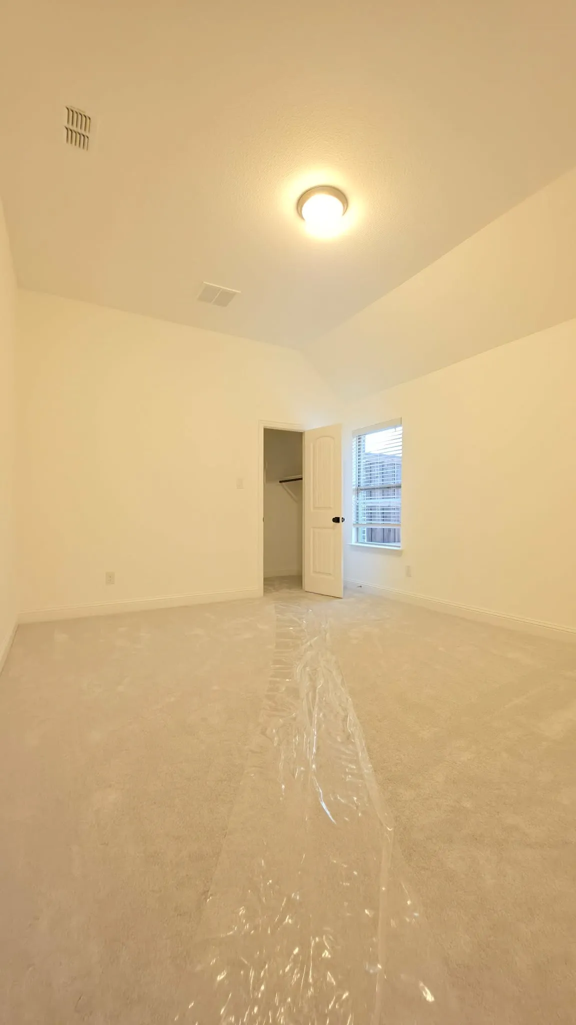 Neutral-toned carpeting with protective covering, vaulted ceiling, and recessed lighting