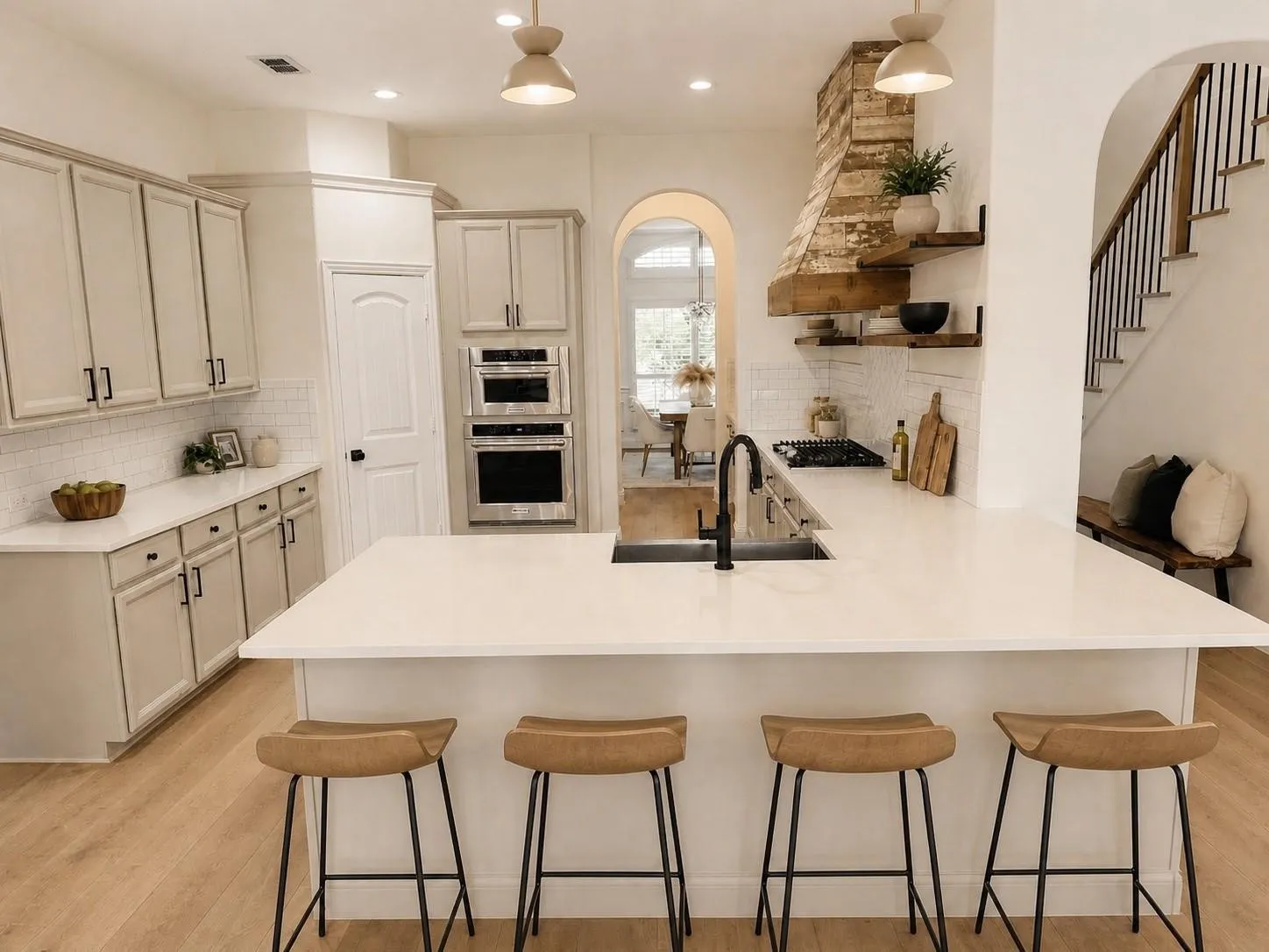 Spacious kitchen featuring an expansive island, light-toned cabinetry, built-in stainless steel appliances, a gas cooktop, and wood-finish flooring