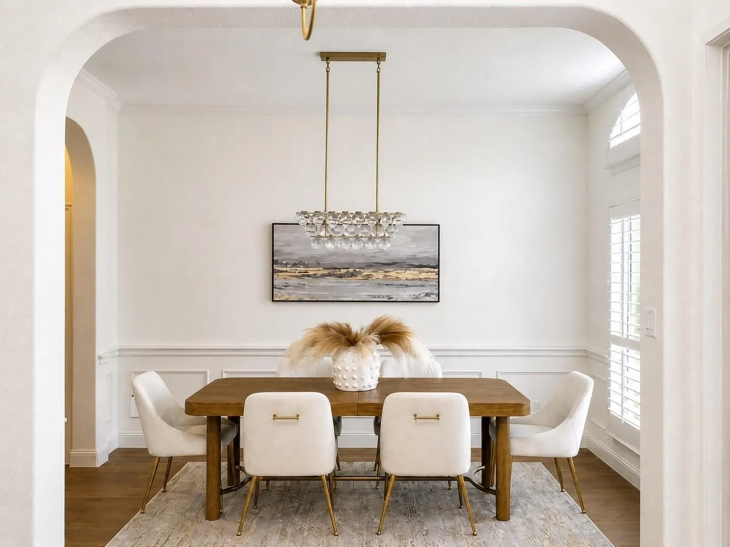 Archways leading to a bright room with wainscoting and wood-finish flooring