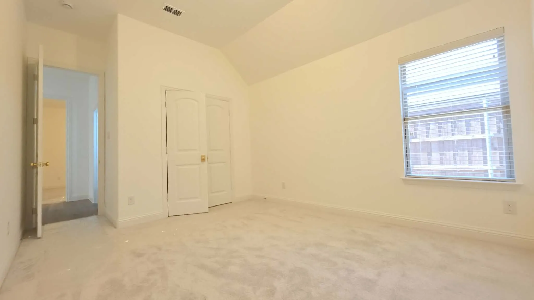 Vaulted ceiling, wall-to-wall carpeting, single window with blinds, and white bi-fold closet doors