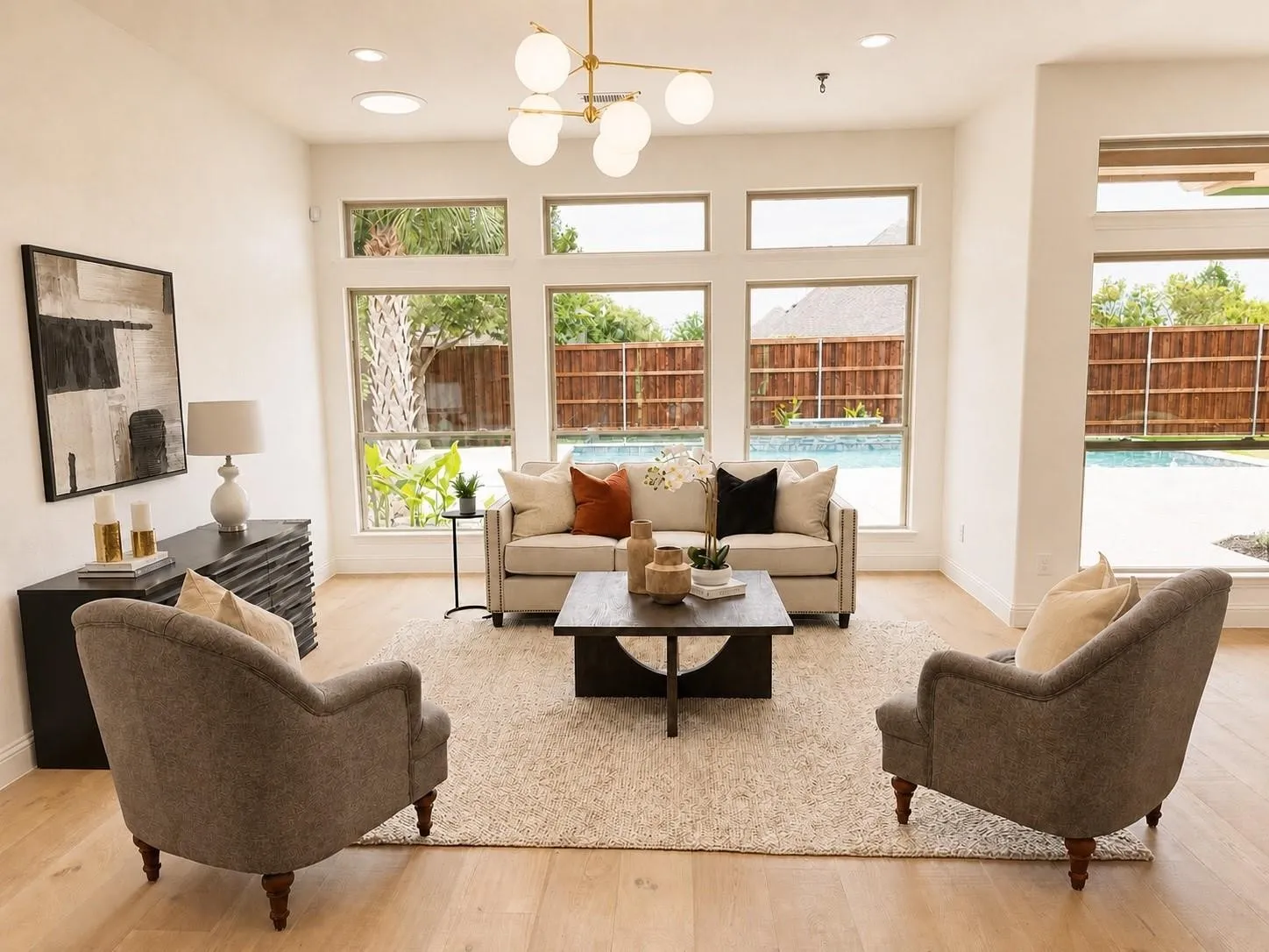 Expansive windows, light wood-finish flooring, recessed ceiling lighting, and a contemporary chandelier