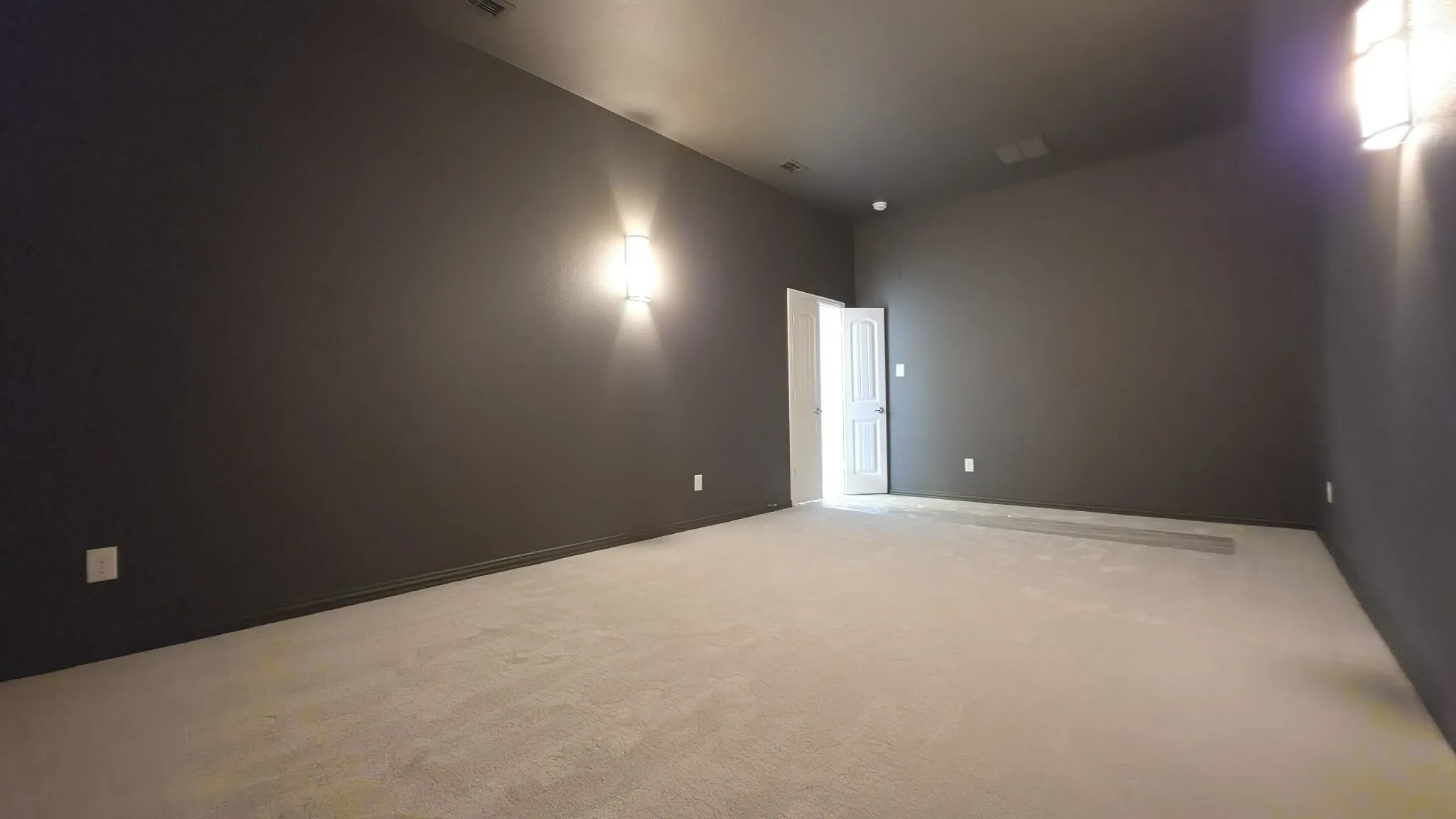 Wall-mounted sconces illuminate dark gray walls