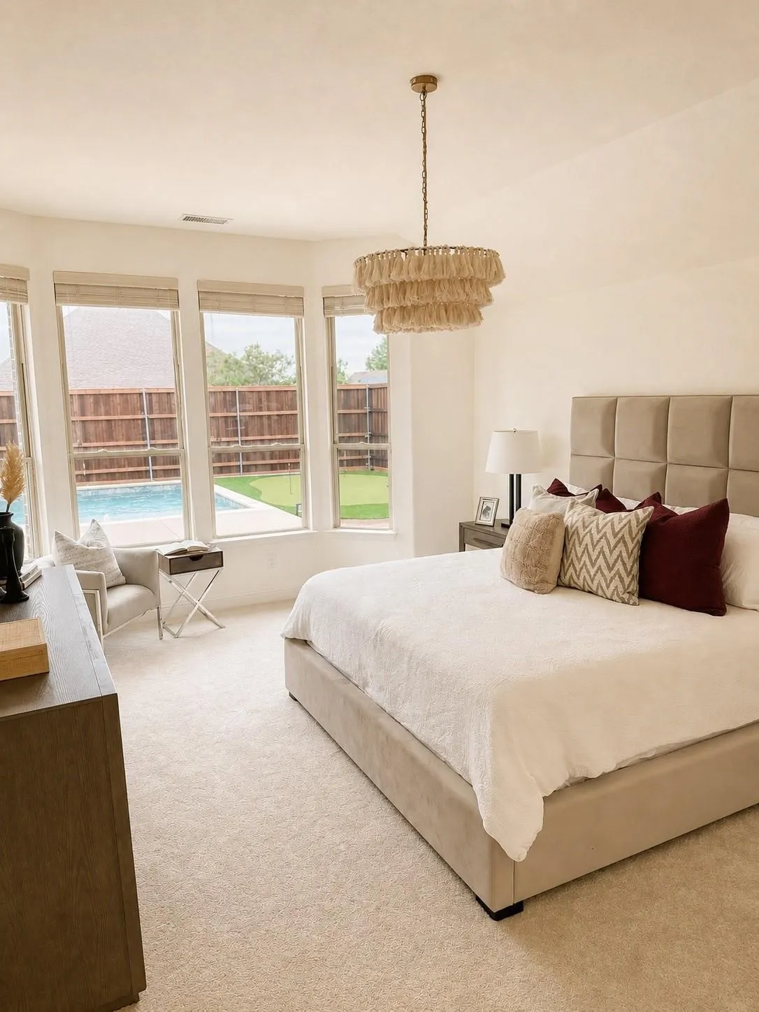 Recessed bay window with multiple glass panes, contemporary tiered chandelier, neutral wall-to-wall carpeting, and light-toned walls