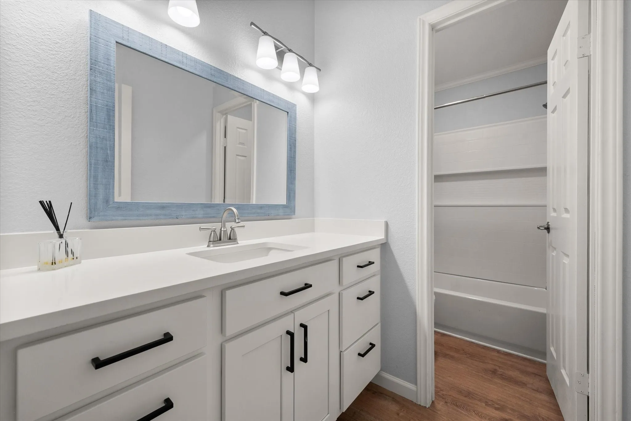Bathroom vanity with white cabinetry, matte black hardware, and an integrated sink