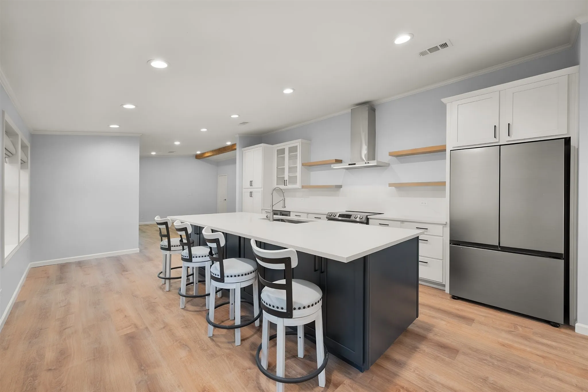 Spacious kitchen featuring a large island with seating, stainless steel appliances, open shelving, and recessed lighting