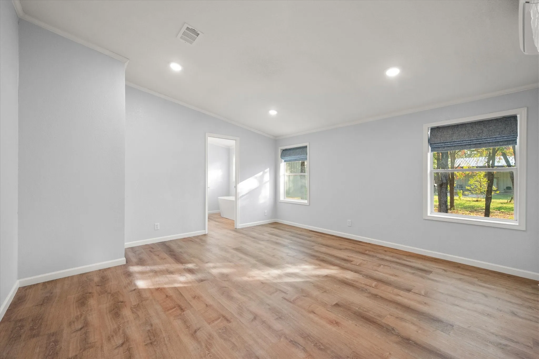 Wood-finish flooring, recessed lighting, and multiple windows with blinds