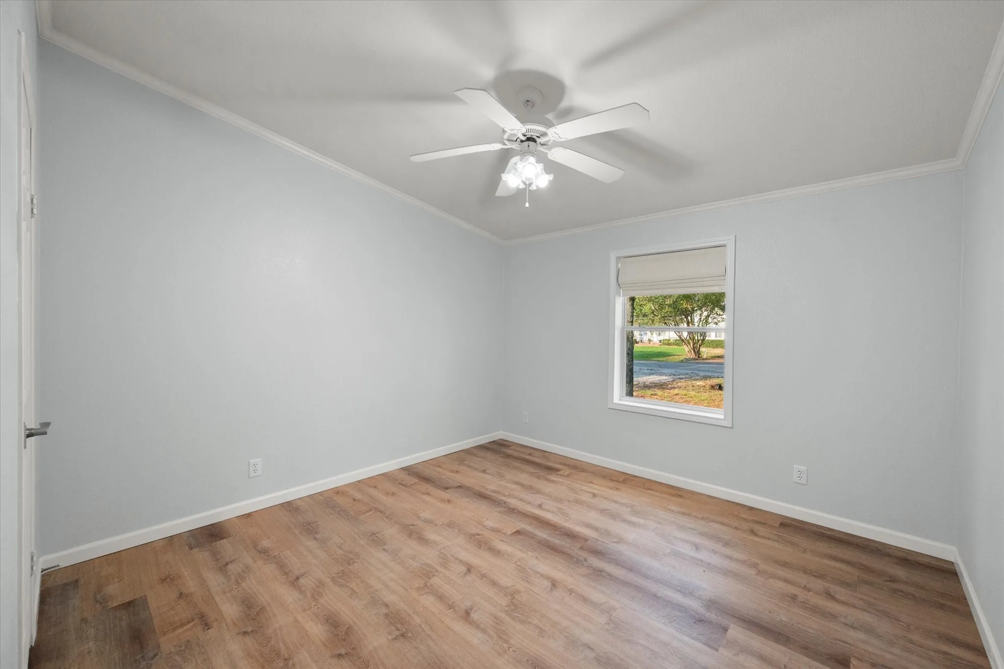 Wood-finish flooring, light blue wall paint, and a ceiling fan with integrated lighting