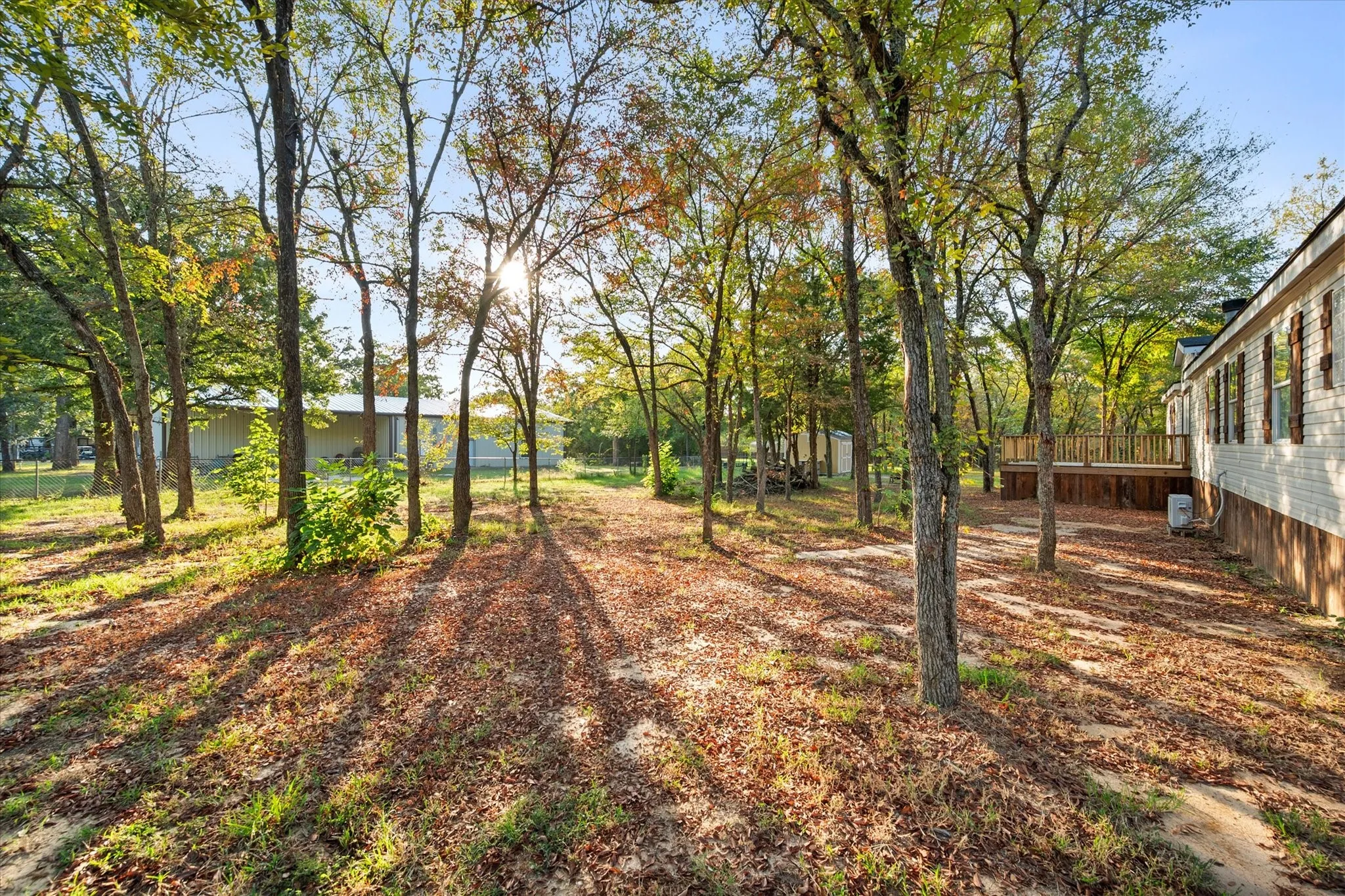 Expansive wooded lot featuring mature trees, a multi-level wood deck, and a white siding exterior