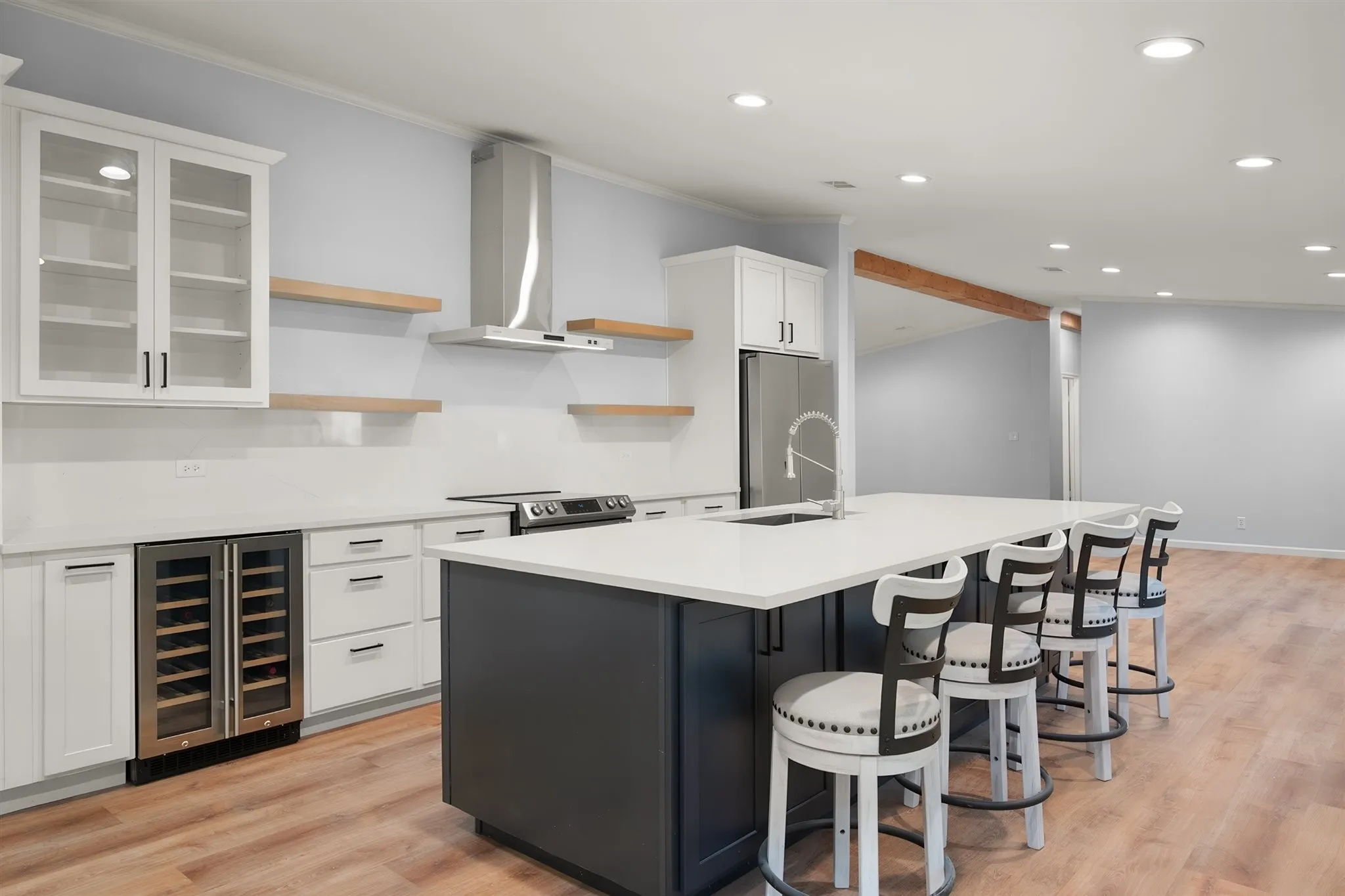 Modern kitchen featuring white cabinetry, a large center island with seating, stainless steel appliances, and wood-finish flooring