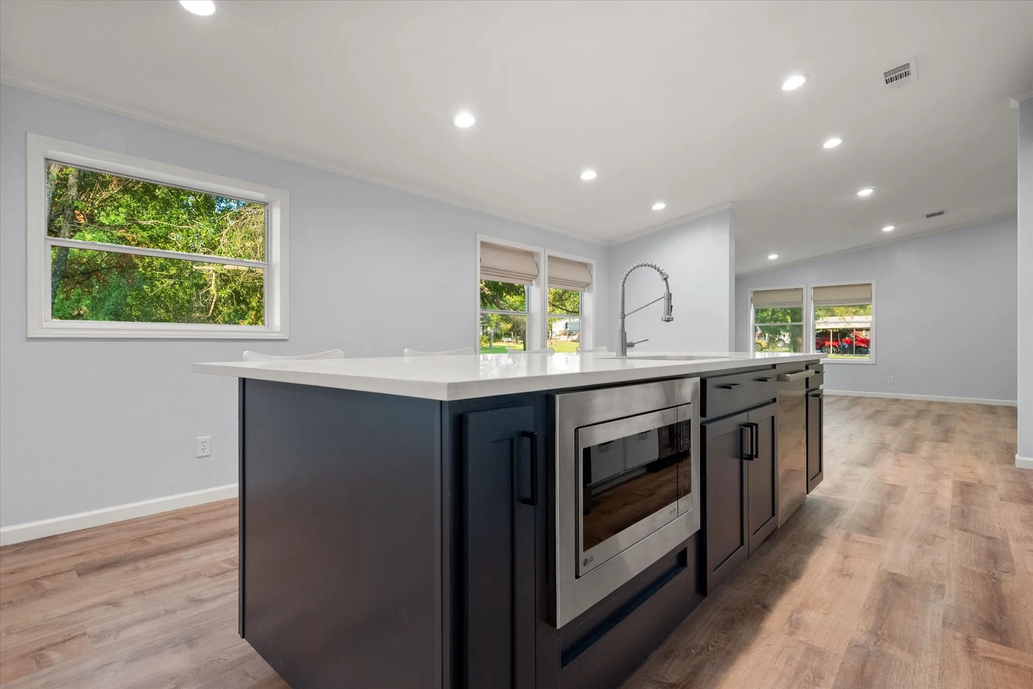 Kitchen island with white countertop, integrated sink, and stainless steel faucet