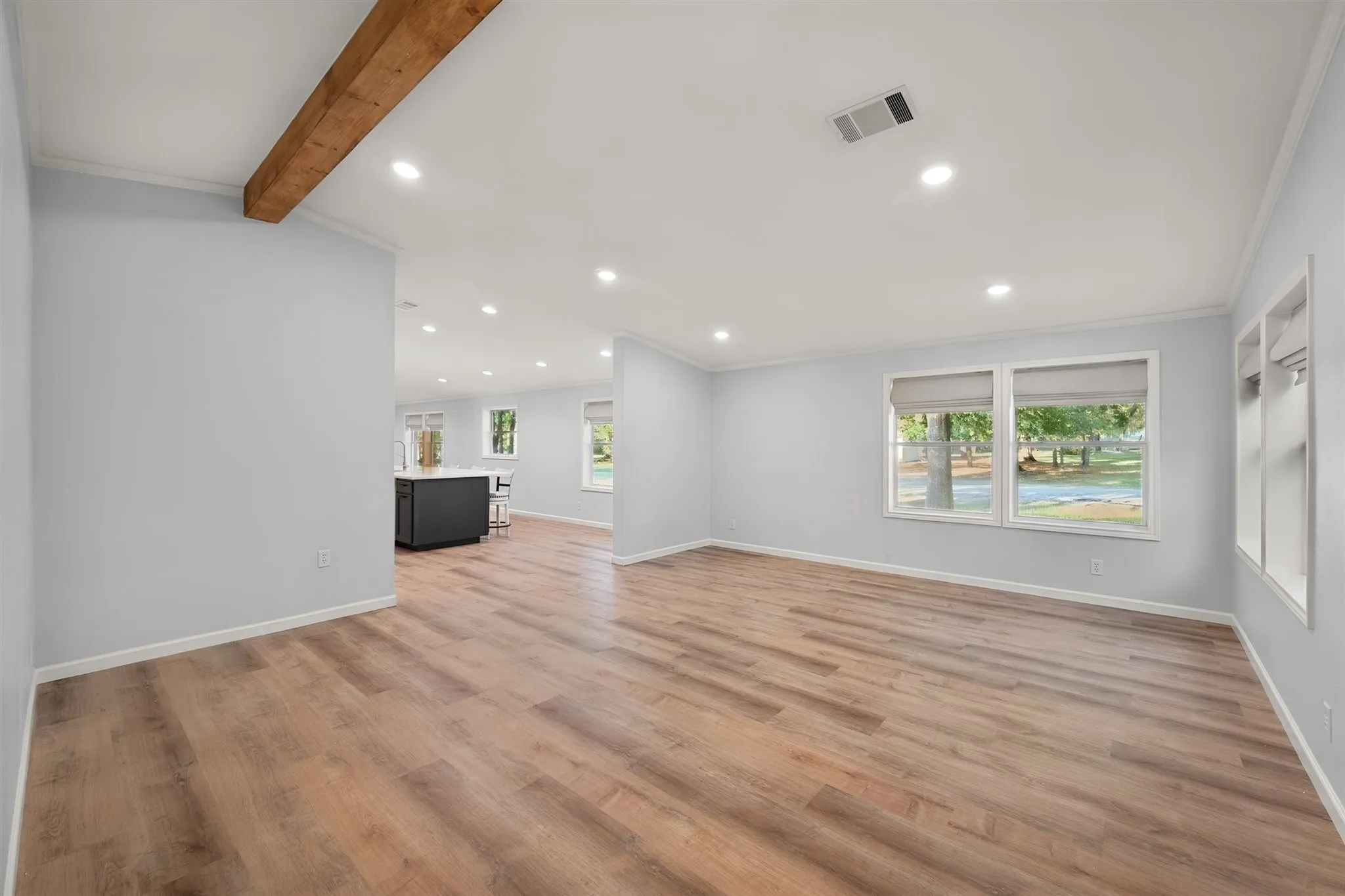 Wood-finish flooring throughout, recessed ceiling lighting, light gray wall tones, and white window trim