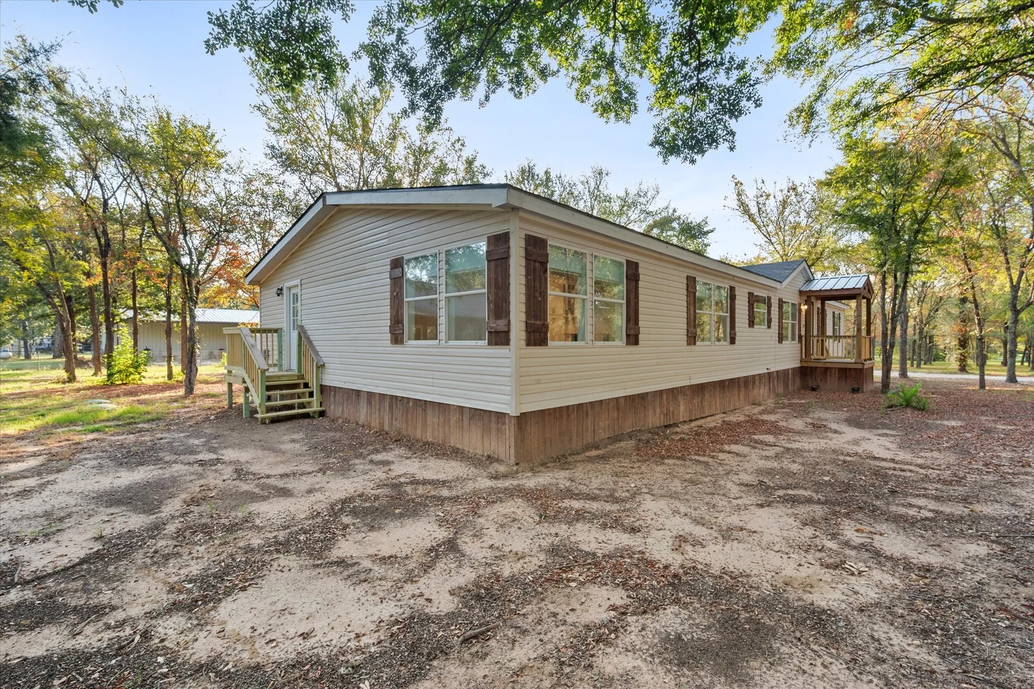 Siding exterior with decorative shutters, covered entry porch, and a second entrance with a wooden staircase
